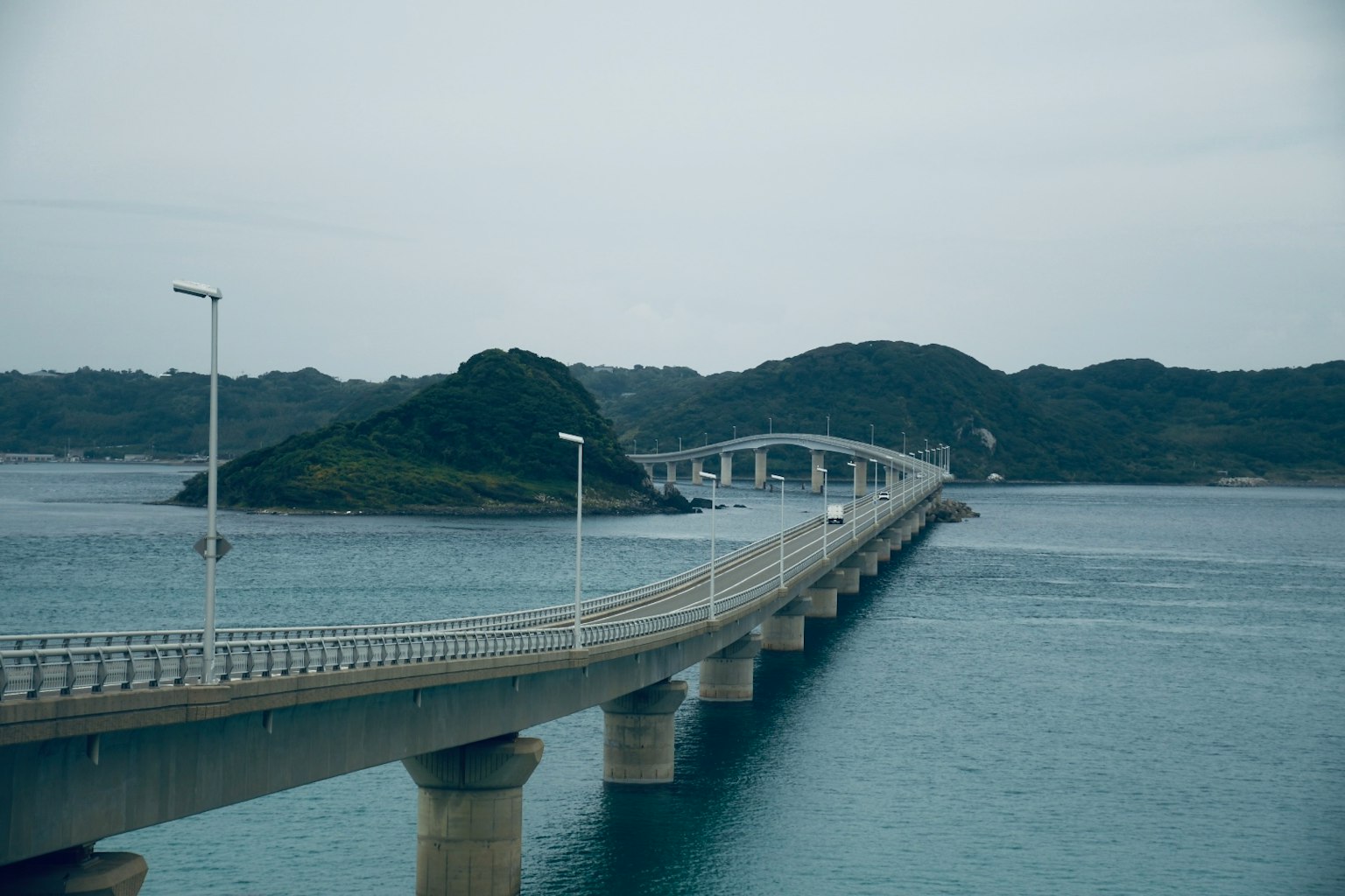 Un long pont s'étendant sur la mer avec des îles vertes environnantes