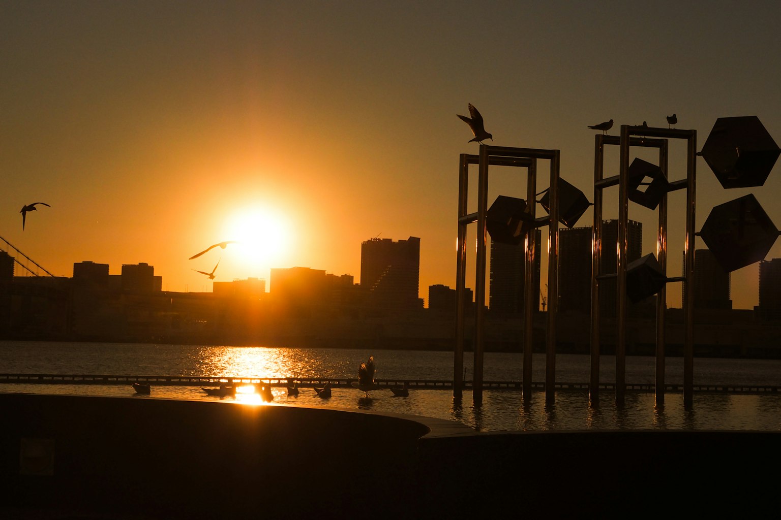 Silhouette d'une ville au coucher du soleil avec des reflets sur l'eau
