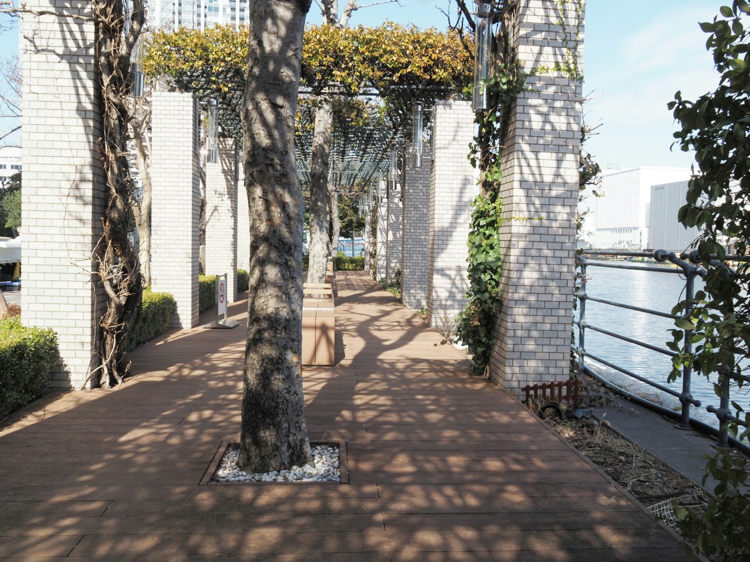 Sendero con sombras de árboles y estructura de arco rodeada de muros blancos