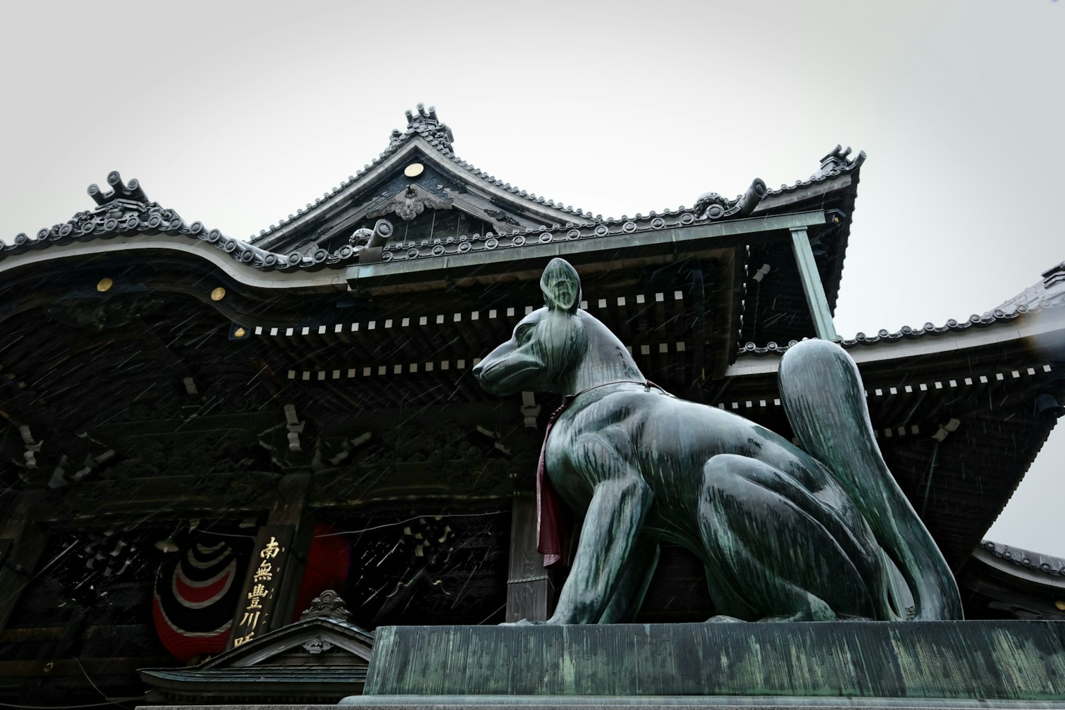 Statua in bronzo di un cane di fronte a un santuario tradizionale