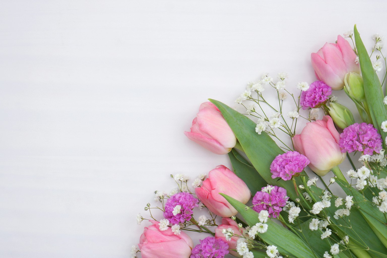 Arreglo de tulipanes rosas y pequeñas flores blancas