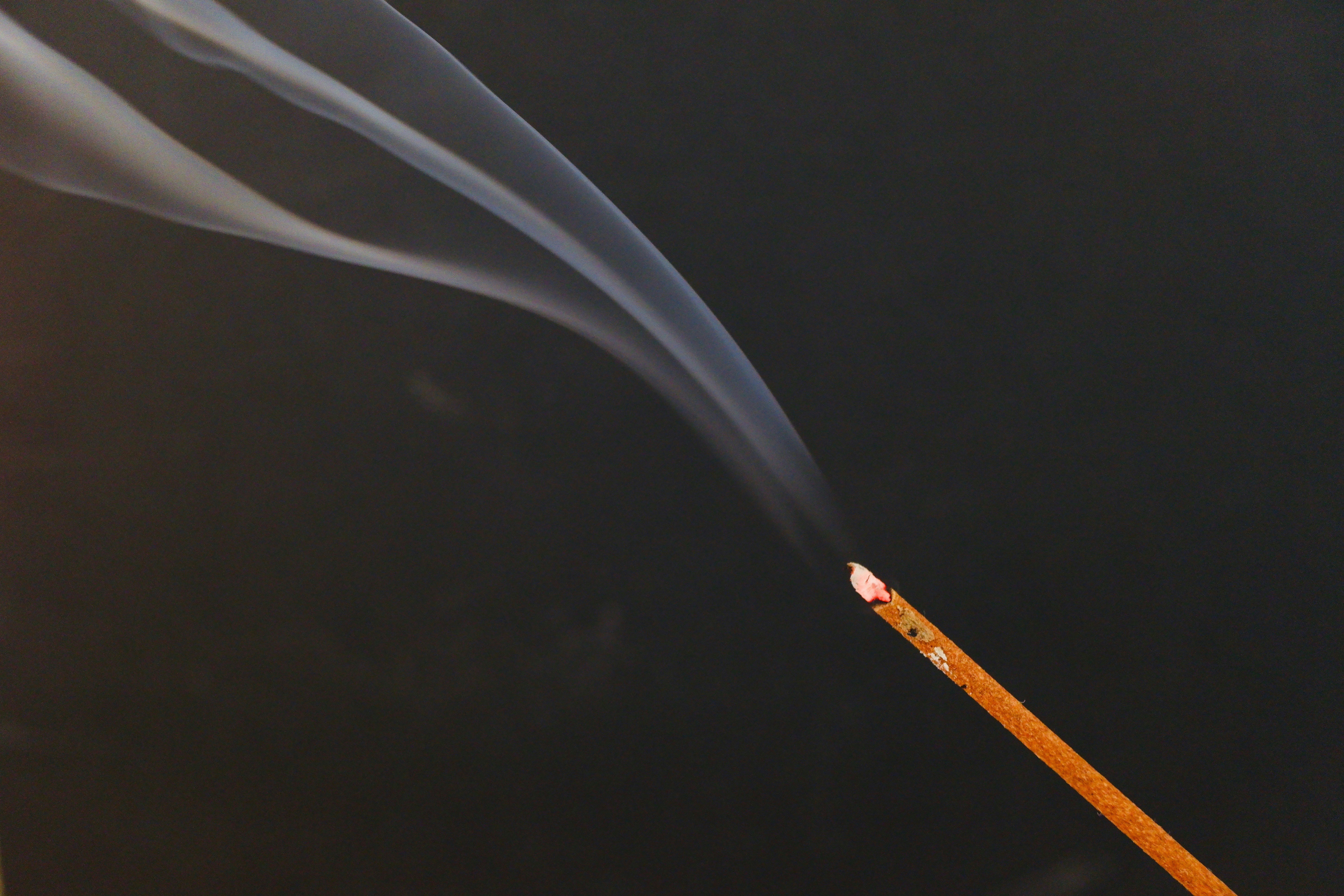 ujung rokok yang membara dengan asap di latar gelap