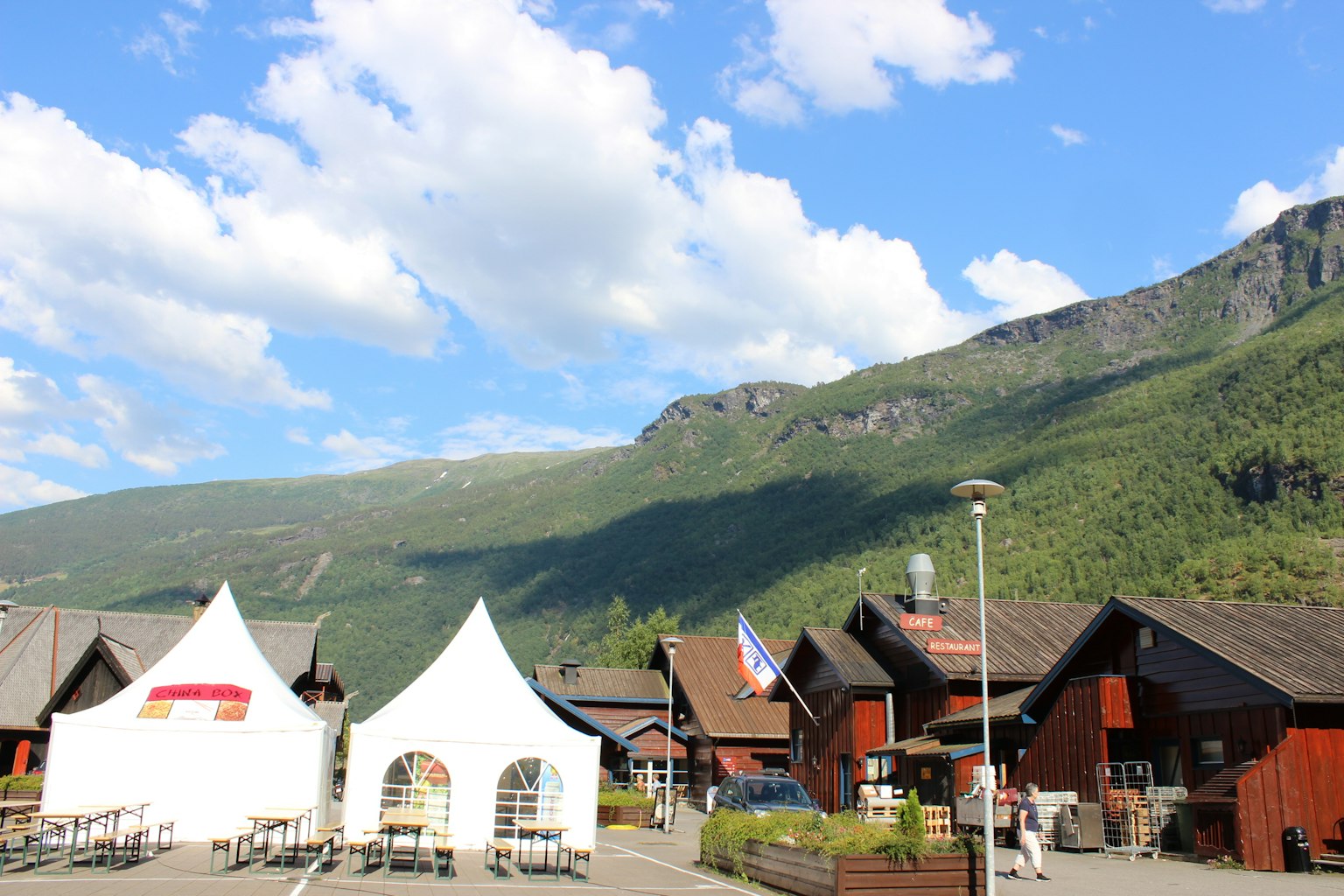 Scenic view of a Norwegian village with mountains in the background white tents and wooden buildings in a lush green setting