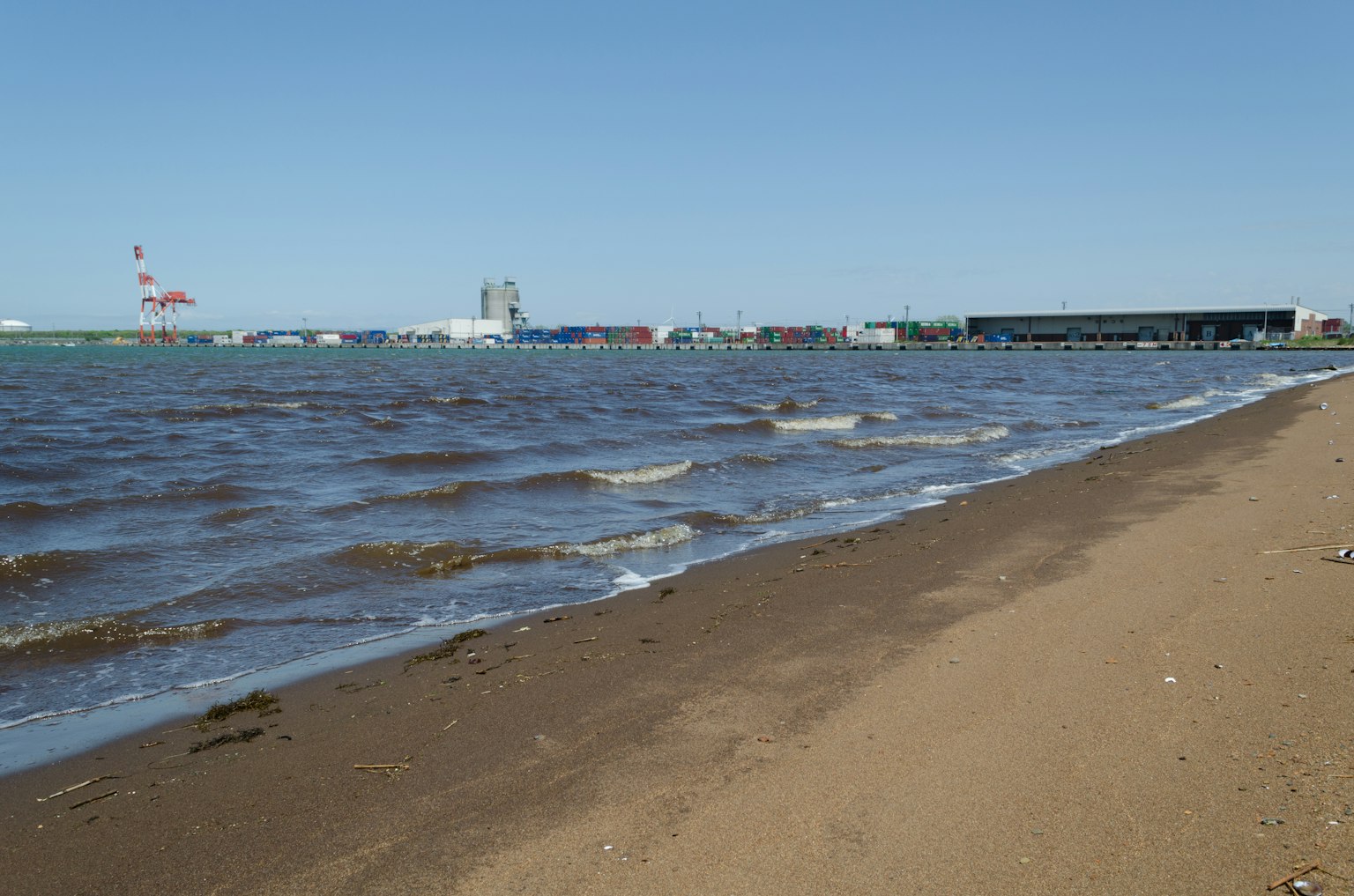 Vista escénica de una playa de arena con olas y edificios distantes