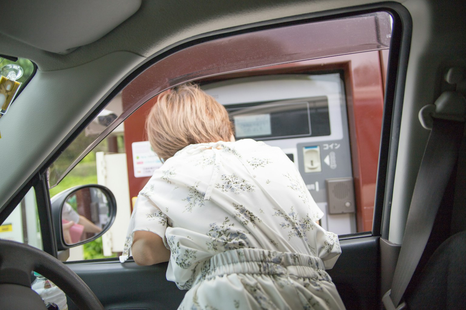 一名女性从车窗外探出身子使用ATM