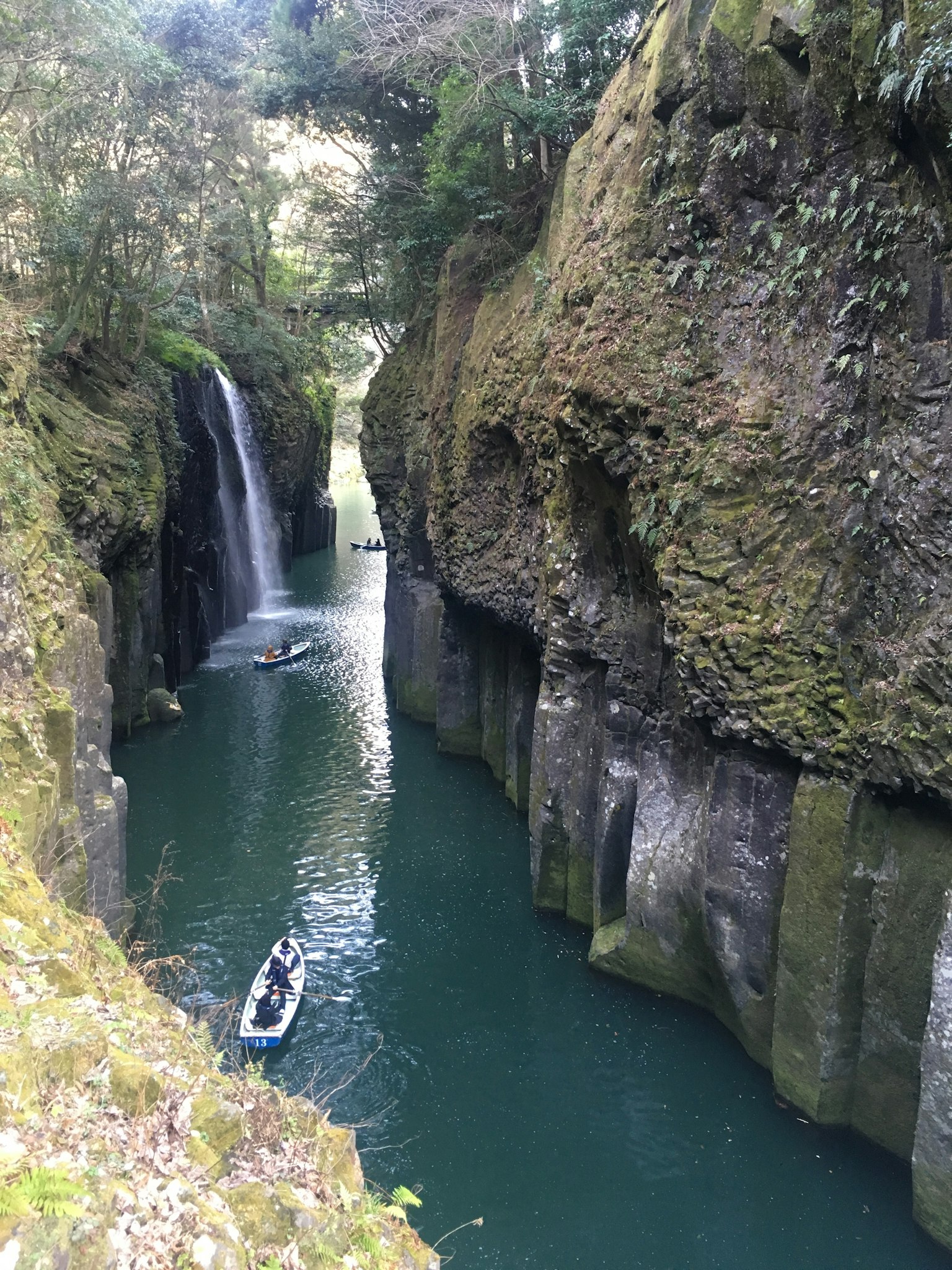 A lush green canyon with a waterfall and a serene river
