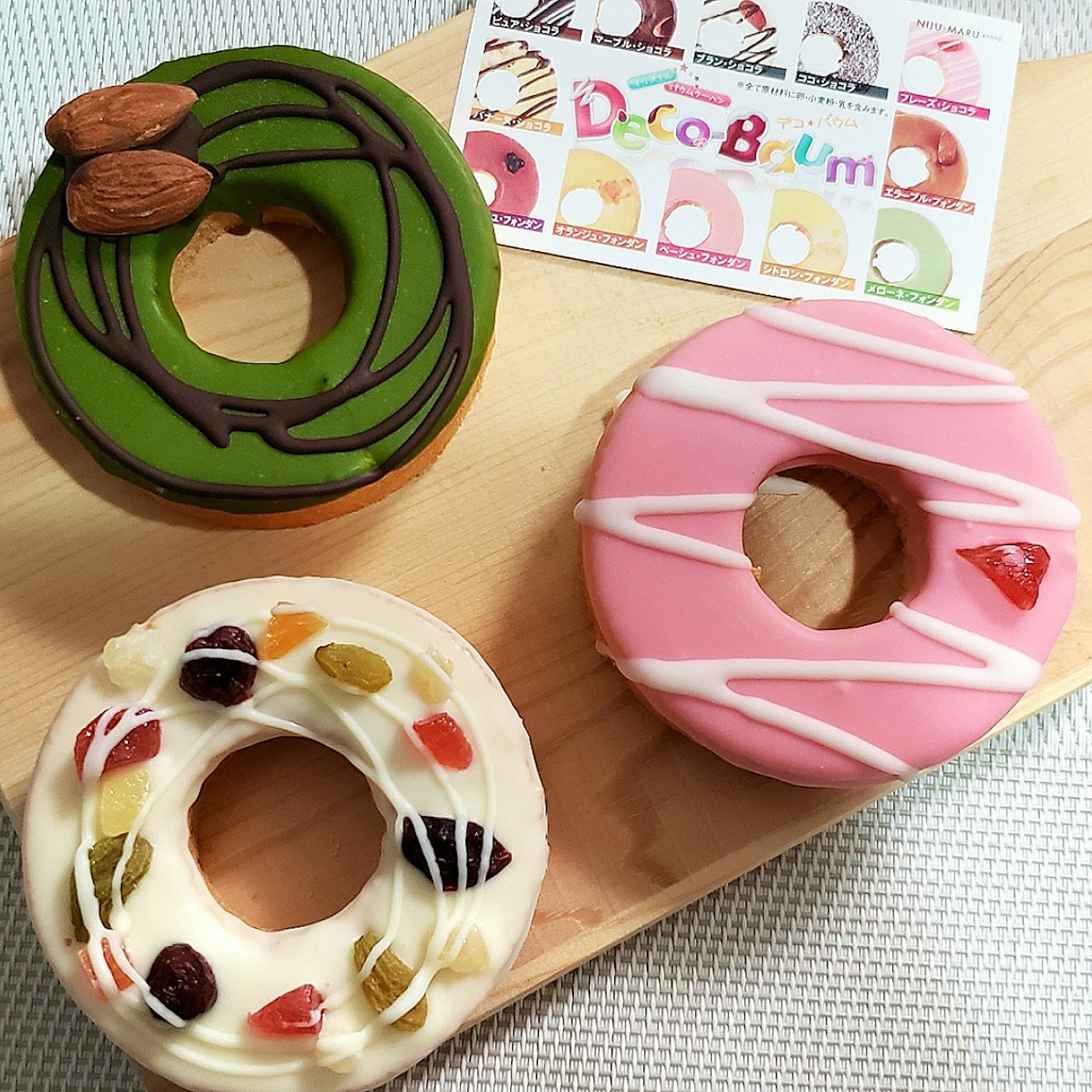 Ba chiếc donut nhiều màu sắc bao gồm donut trà xanh và donut dâu tây hồng với lớp phủ trái cây