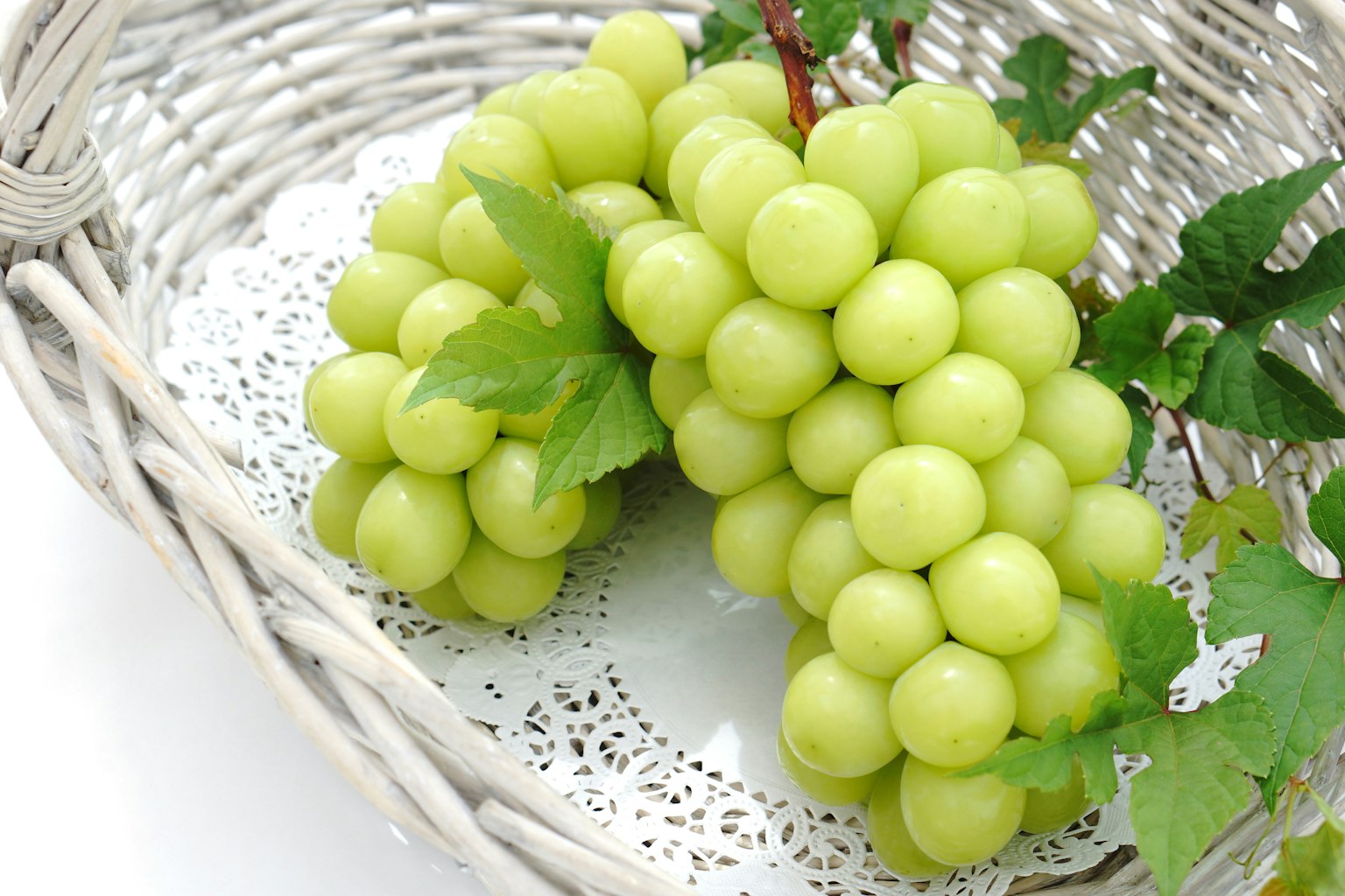 Fresh green grapes and leaves in a white basket