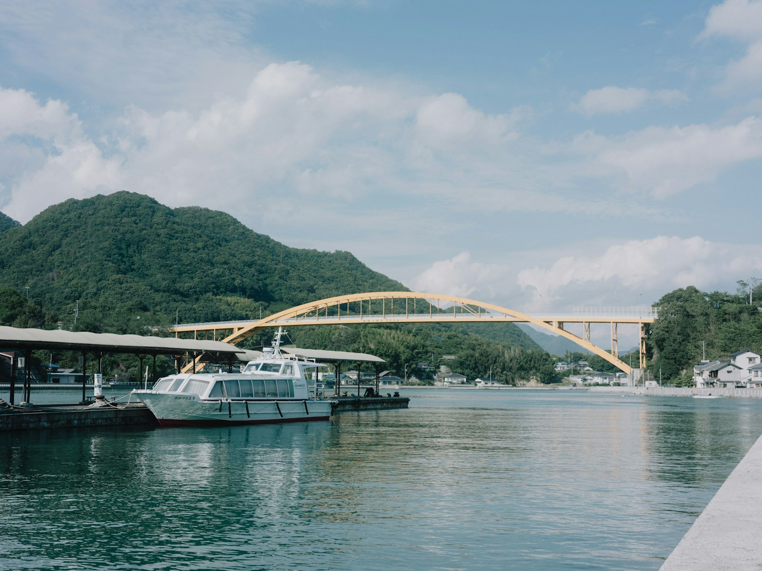 Vista panoramica del fiume con un ponte ad arco giallo e barche tranquille