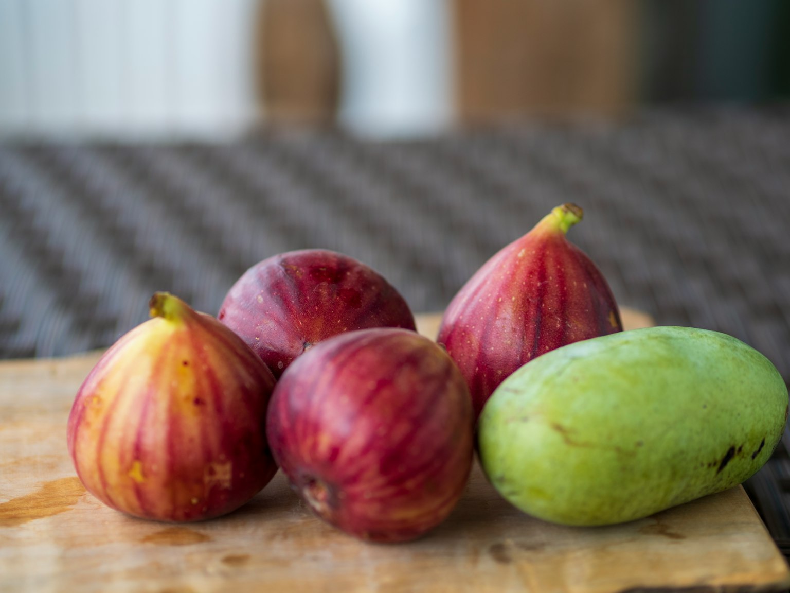 Fik merah-ungu dan mangga hijau disusun di atas papan kayu
