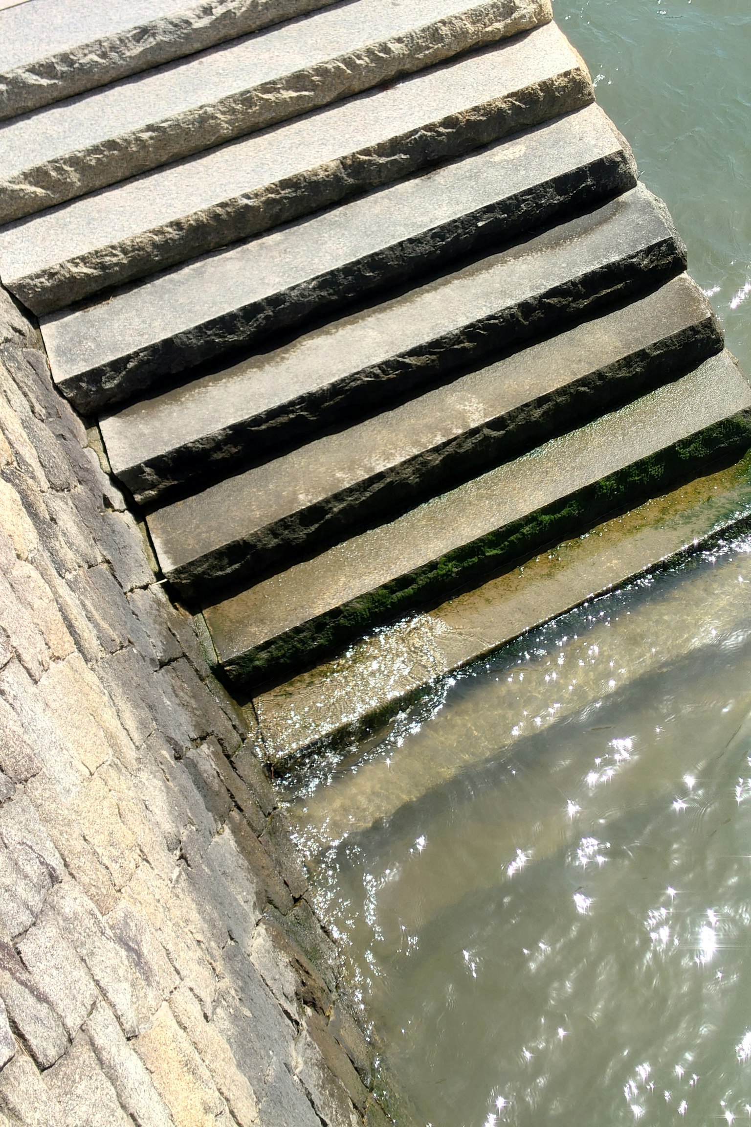 Immagine di scale in pietra che conducono nell'acqua con riflessi di luce sulla superficie