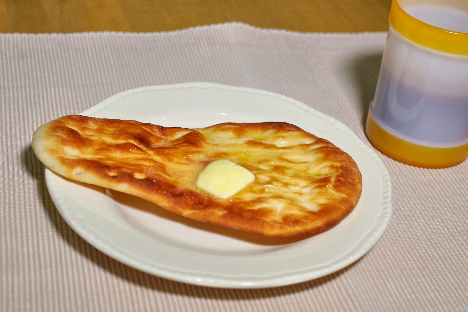 Freshly baked naan bread with butter on a white plate