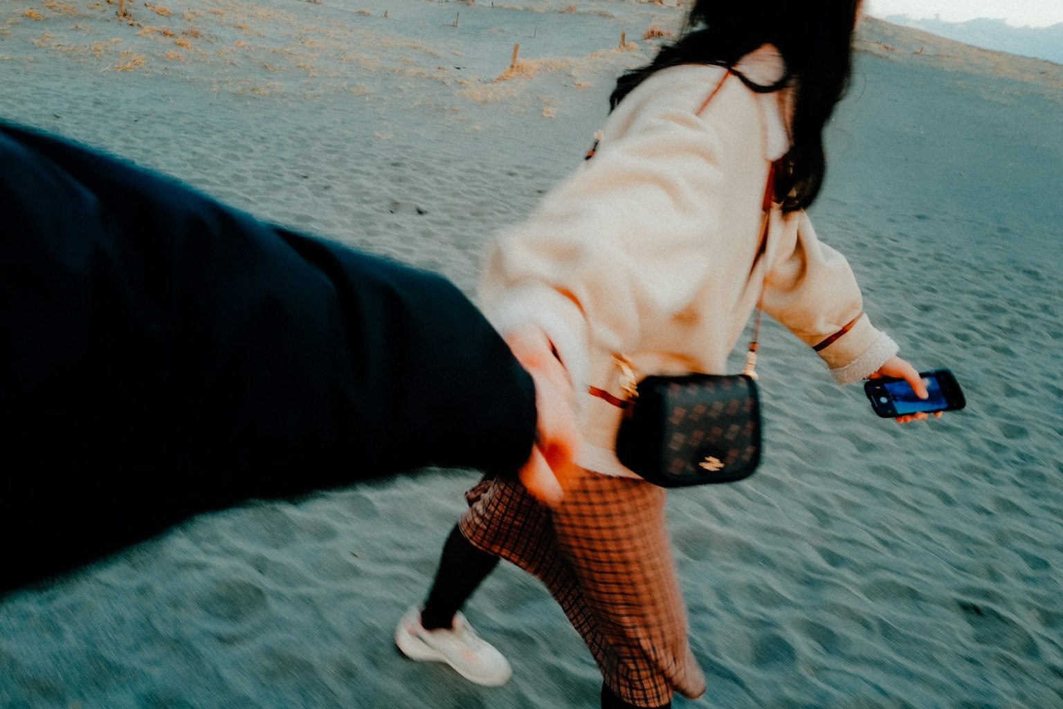 Cặp đôi nắm tay nhau trên bãi biển lúc hoàng hôn