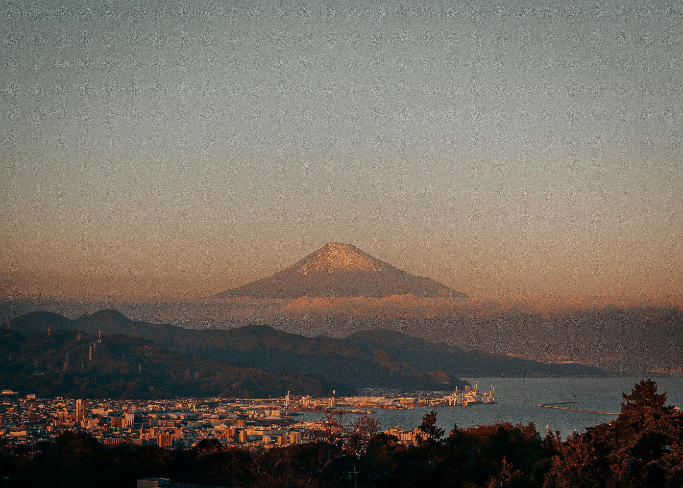 夕暮れの海と街並み、遠くにそびえる富士山