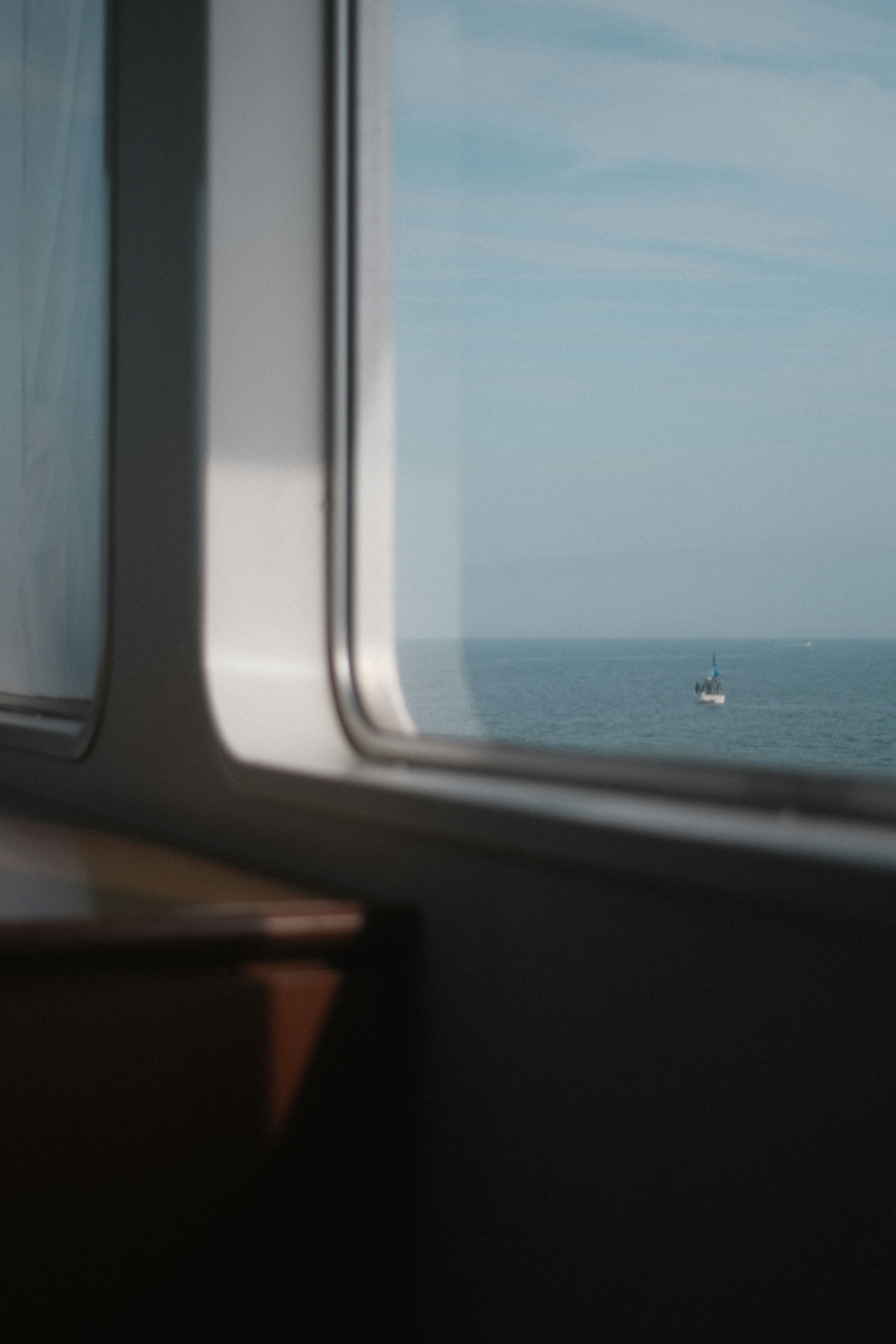 旅先のフェリーの窓から見える海と遠くの船影