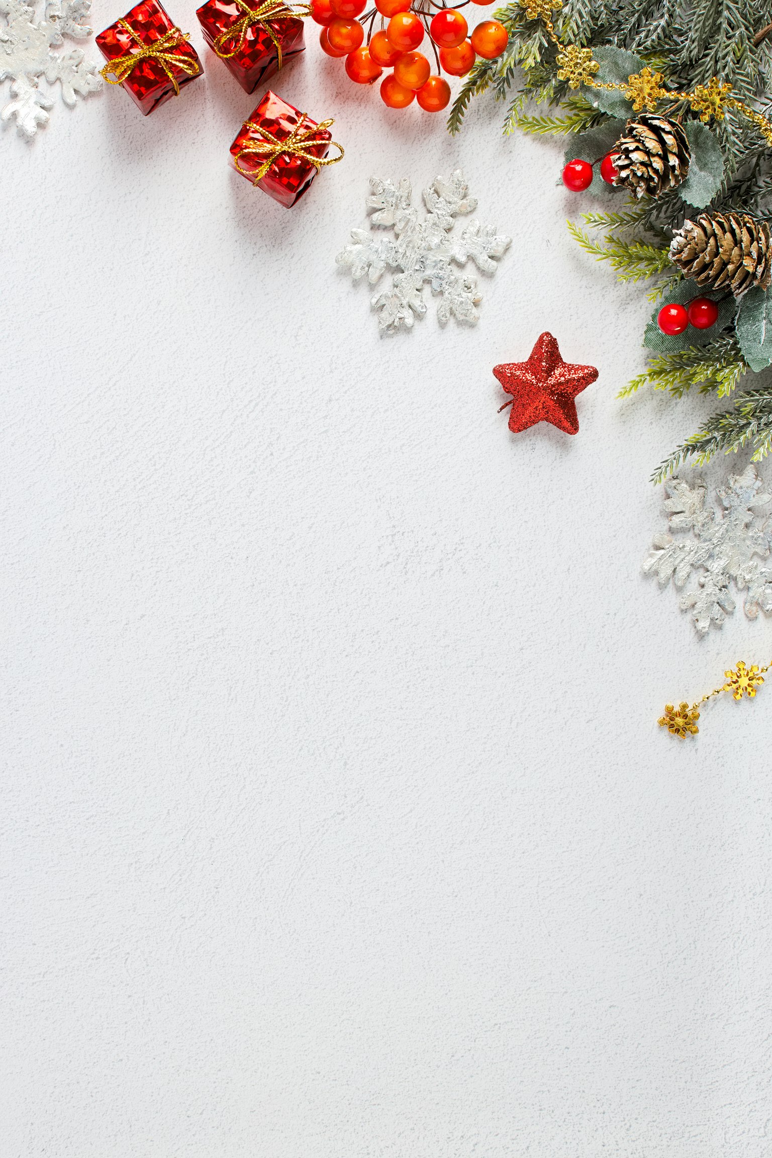 Decorazioni natalizie con scatole regalo rosse e pigne su uno sfondo bianco