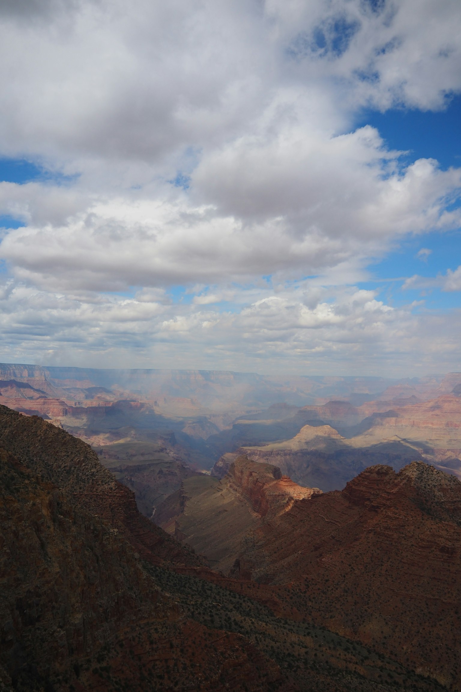 Cảnh quan rộng lớn của Grand Canyon với bầu trời xanh và mây