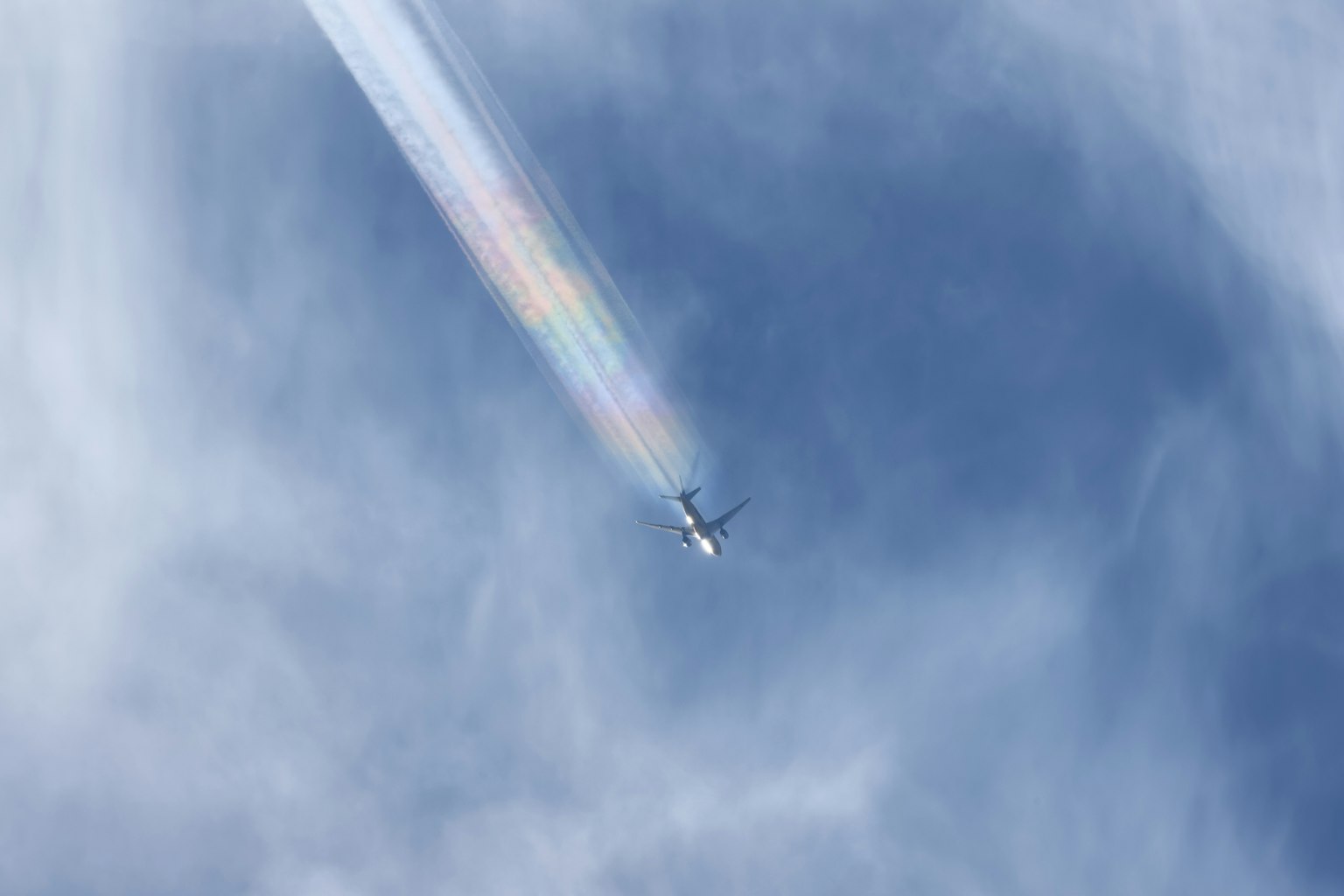 Airplane leaving a rainbow trail in the sky