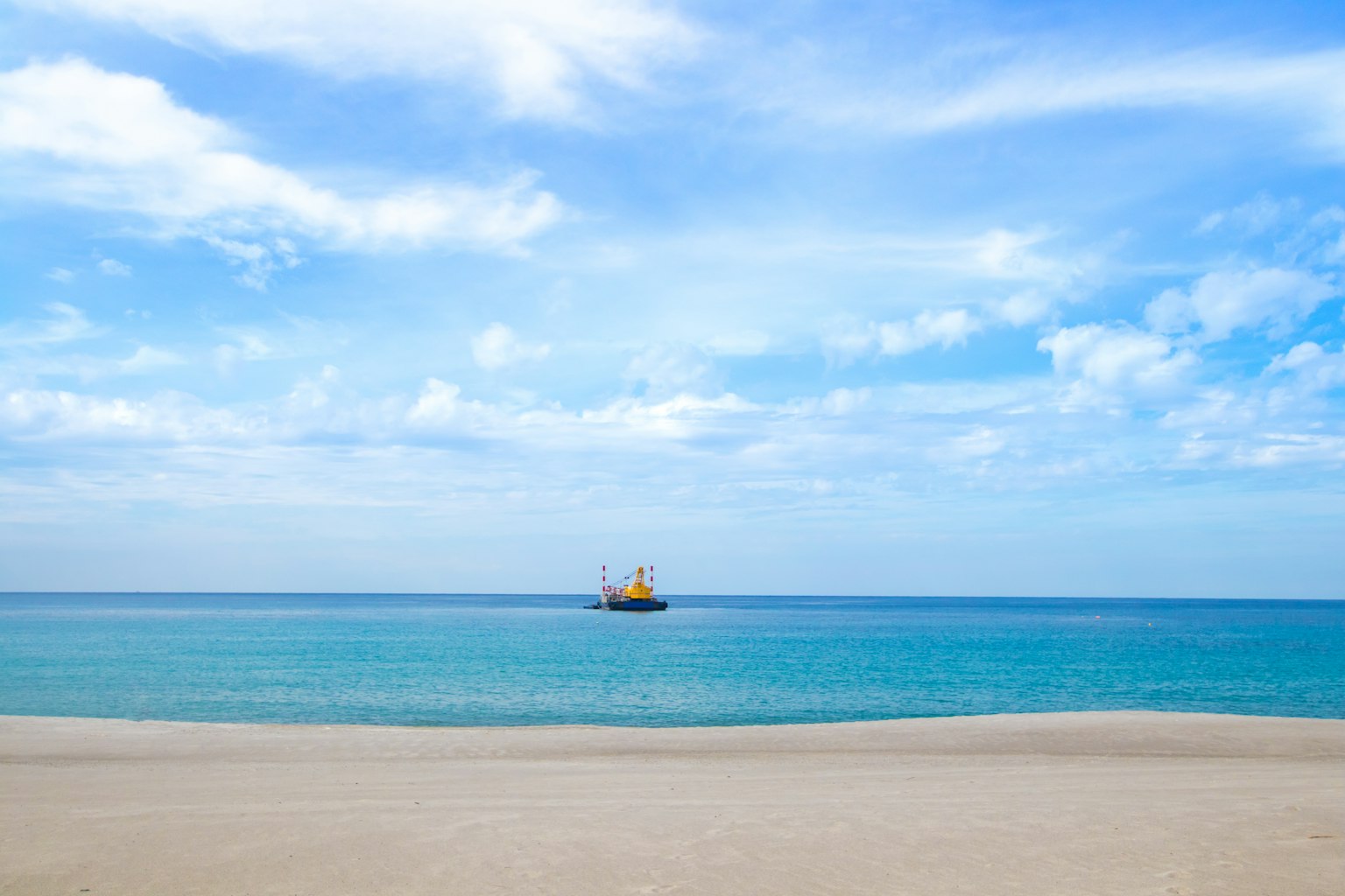 Schöner Strand mit einem Schiff auf dem blauen Meer unter klarem Himmel