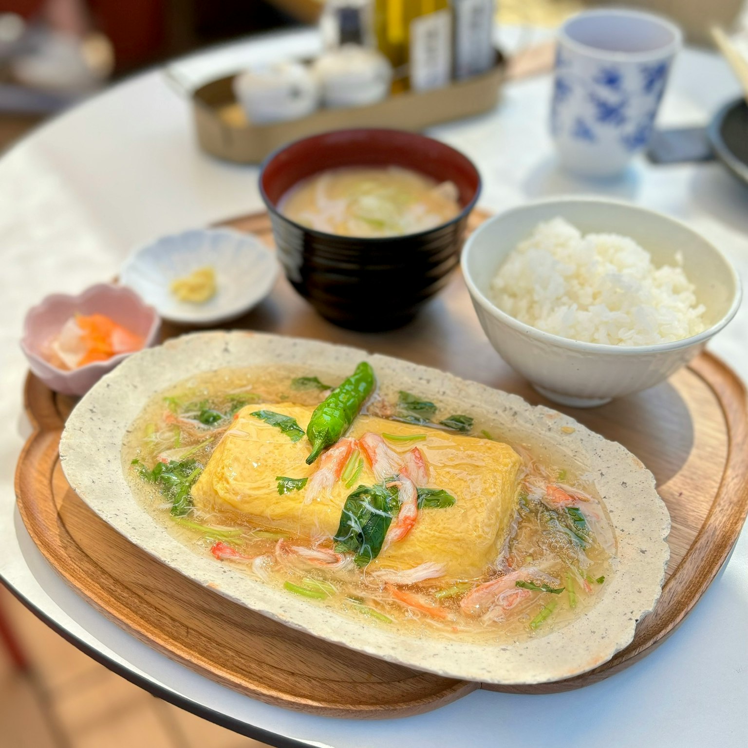 Ein warmes Gericht aus Eiertofu, serviert auf einem Holztablett mit Spargel und Gemüse obenauf