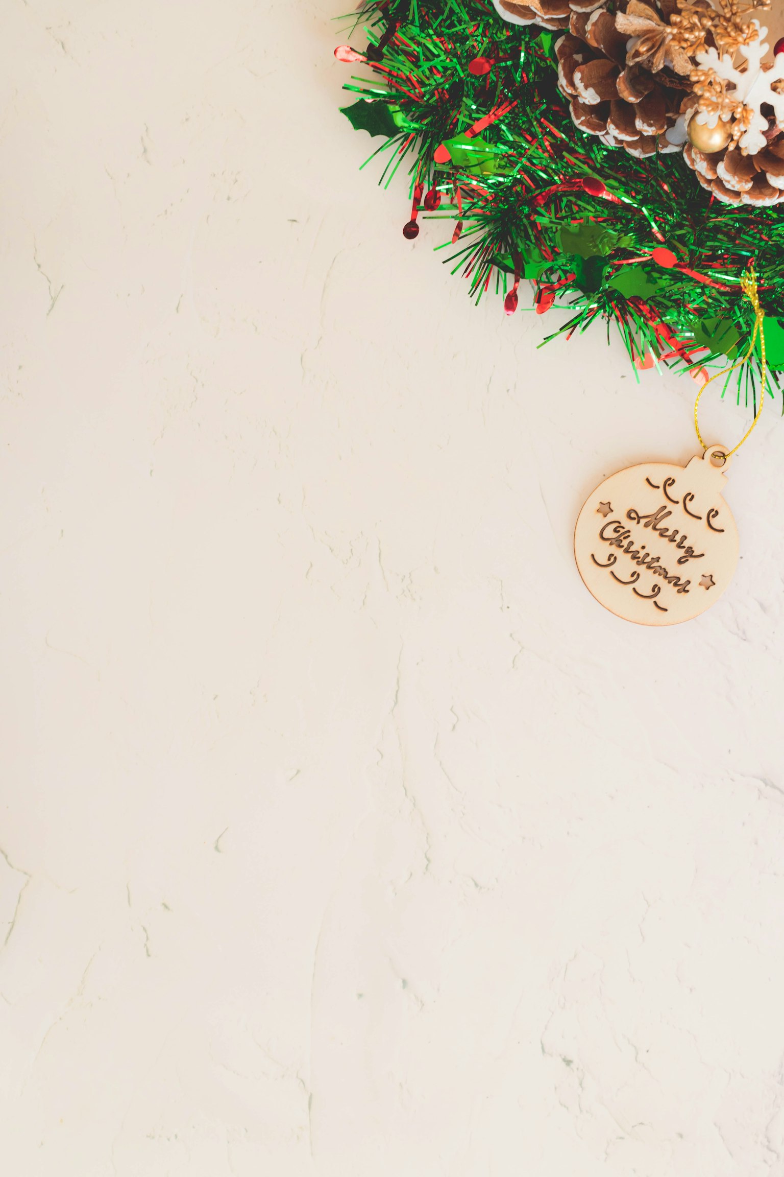 Corona de Navidad con piñas y adorno de madera sobre un fondo claro