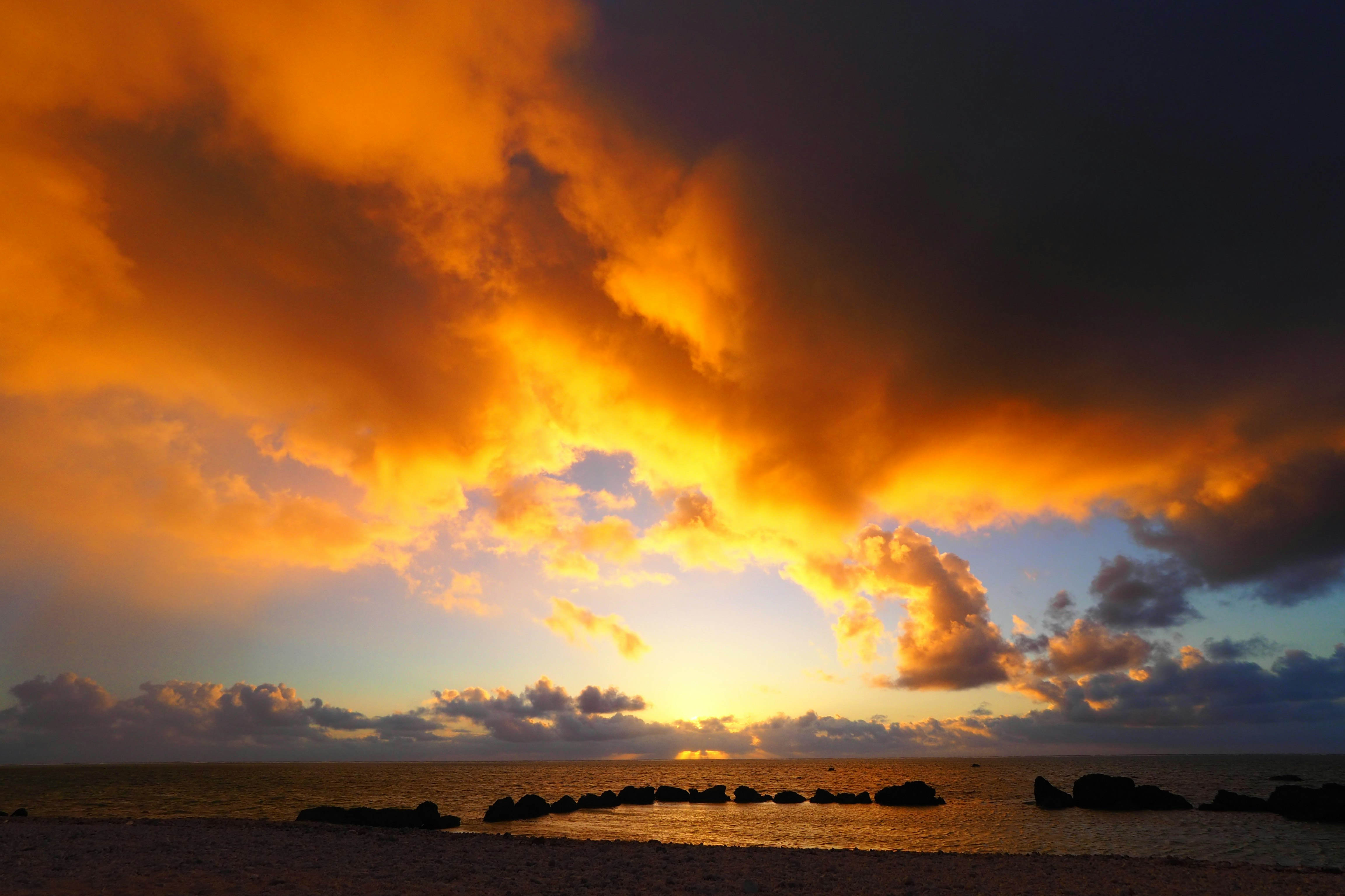 夕焼けの海岸に広がる燃えるような雲と水平線