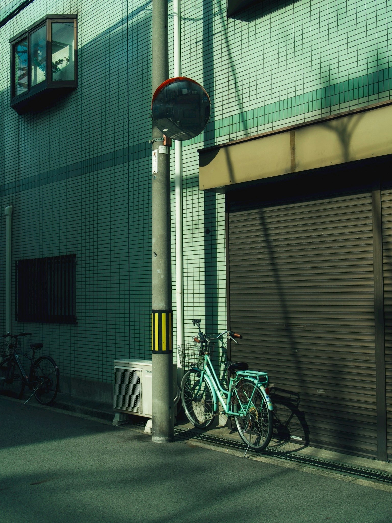 青い自転車が立てかけられた街角の風景 照明の影が壁に映る