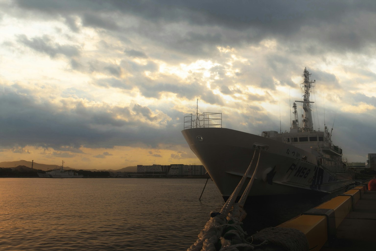 Bateau amarré au port au coucher du soleil avec un ciel nuageux