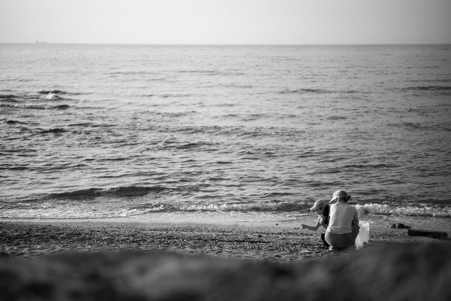 Imagen en blanco y negro de personas sentadas en una playa tranquila