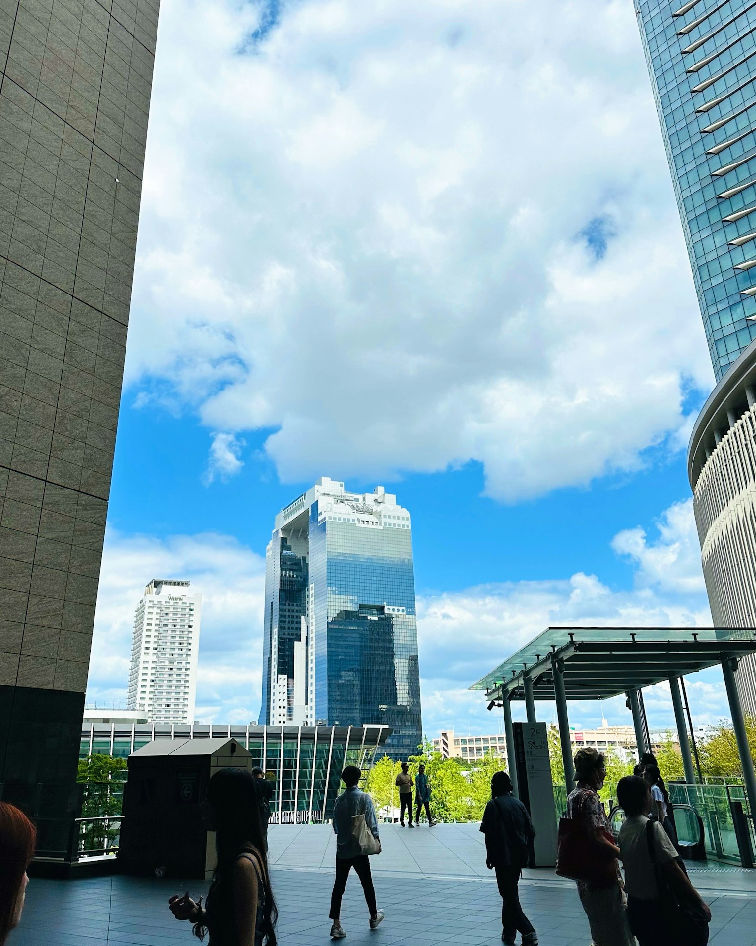 Pemandangan kota dengan gedung pencakar langit di bawah langit biru dan orang-orang berjalan