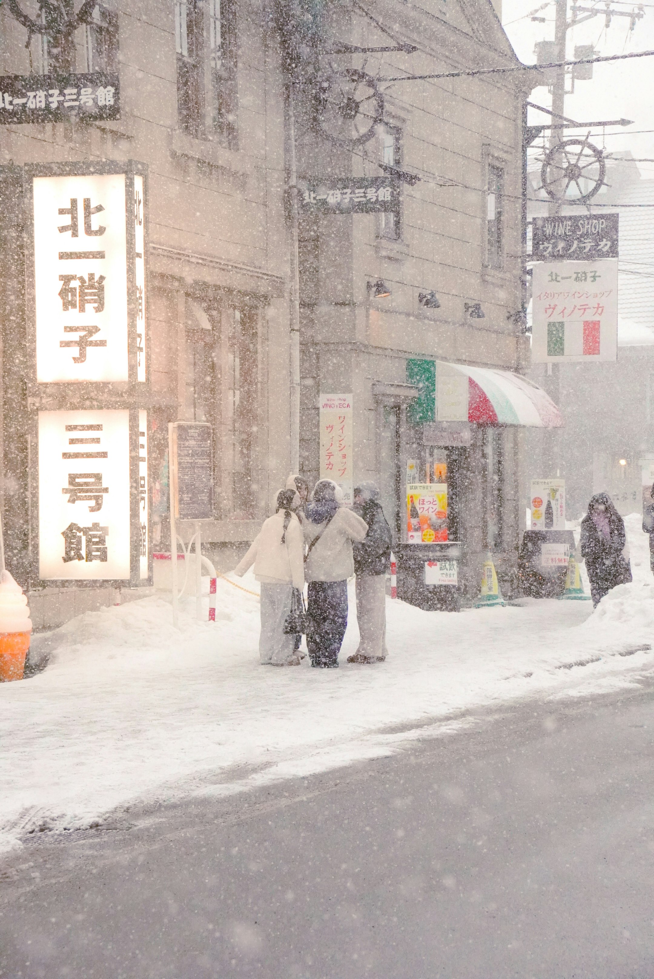 雪の路地で看板の前を歩く人たち