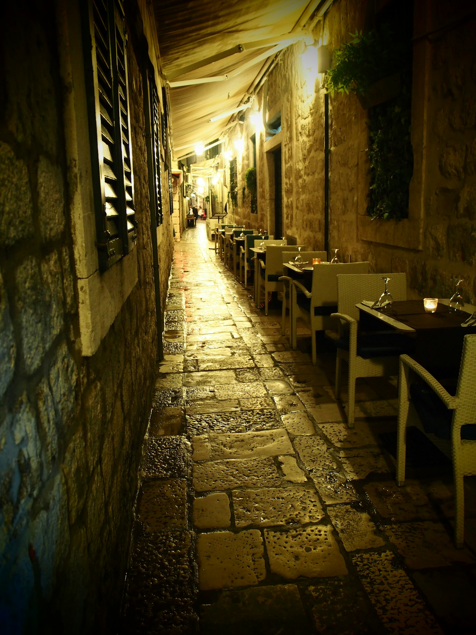Quiet restaurant alley with stone walls and soft lighting