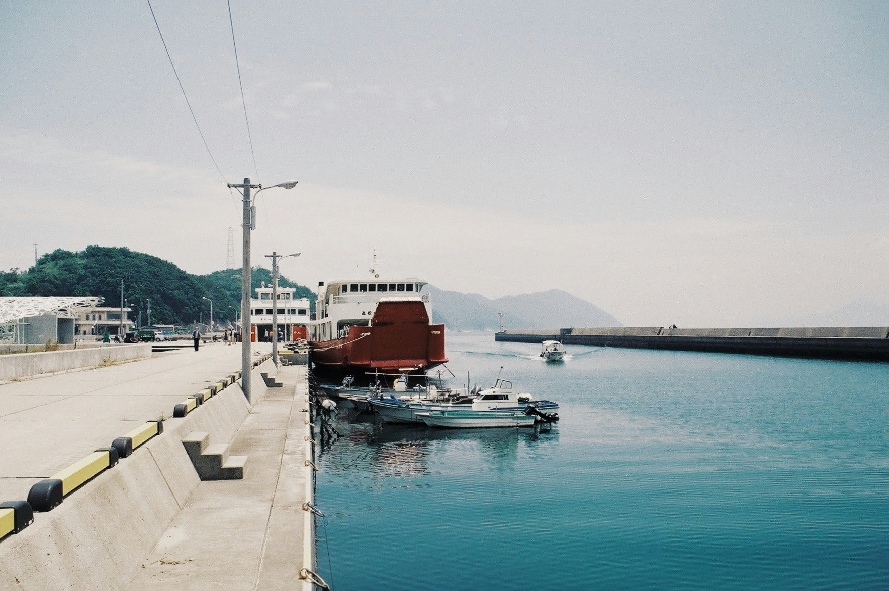 harbor scene with a pier and moored small boats by the sea