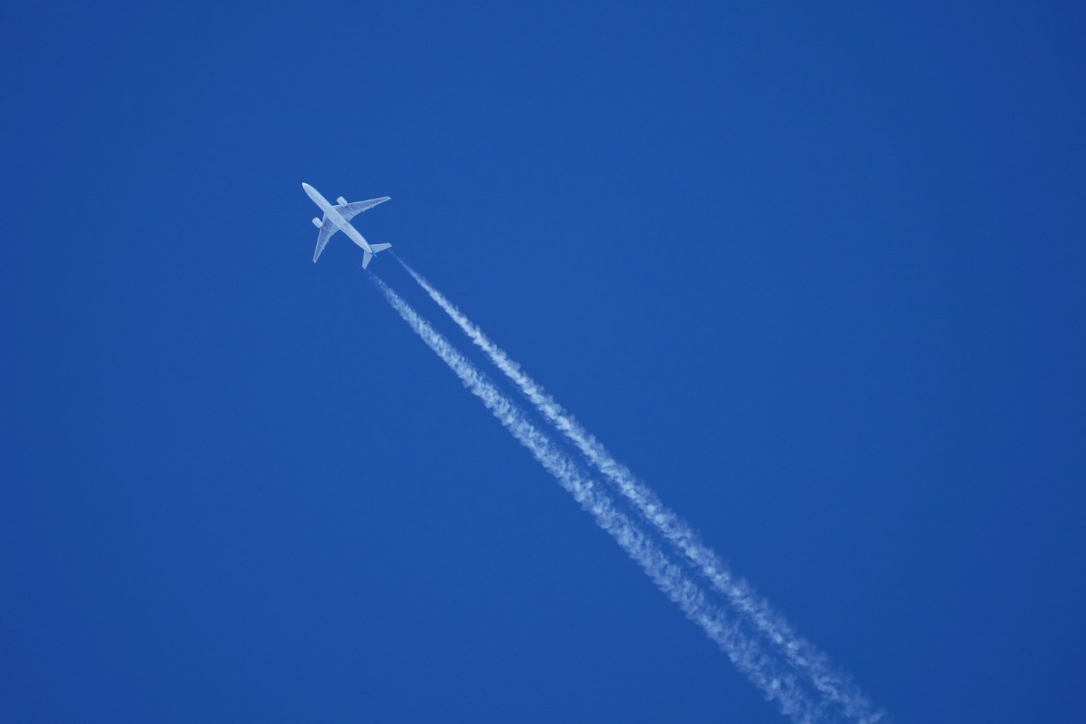 Un avion montant dans un ciel bleu avec des traînées derrière lui