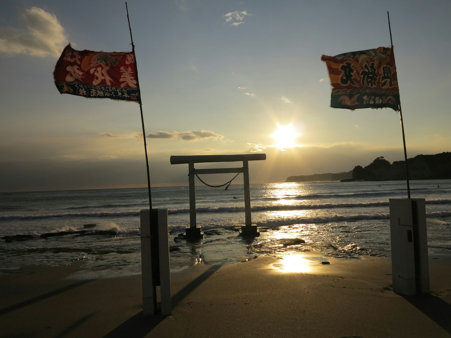 海滩上的鸟居和旗帜与日落