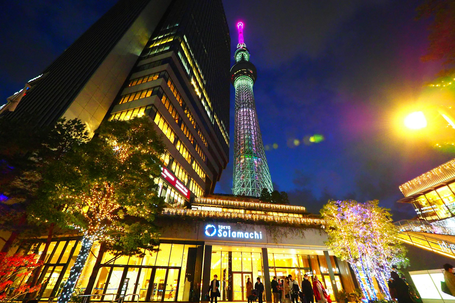 Tokyo Skytree illuminé la nuit avec des bâtiments et des arbres environnants