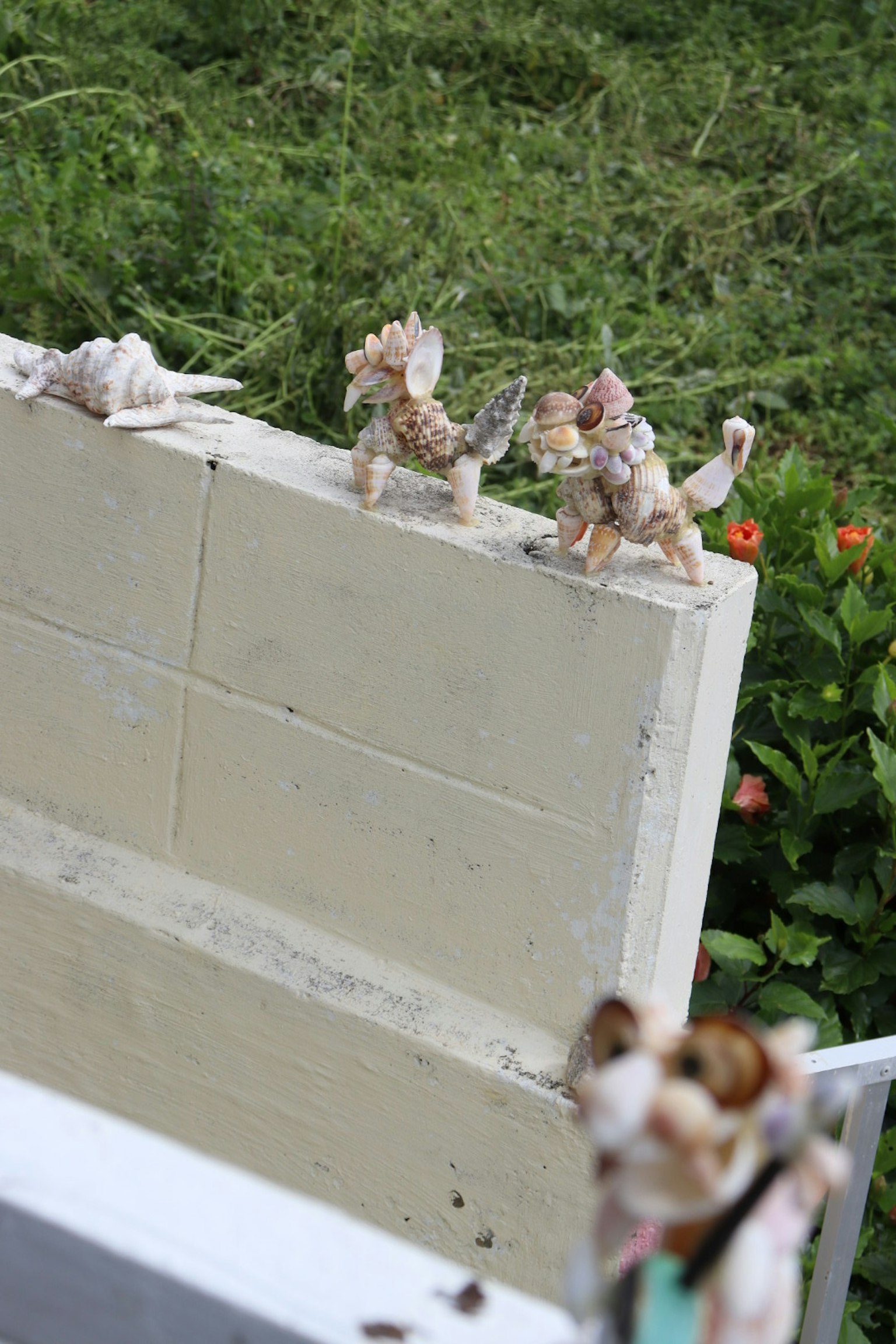 Piccole sculture di animali su un muro con piante verdi sullo sfondo