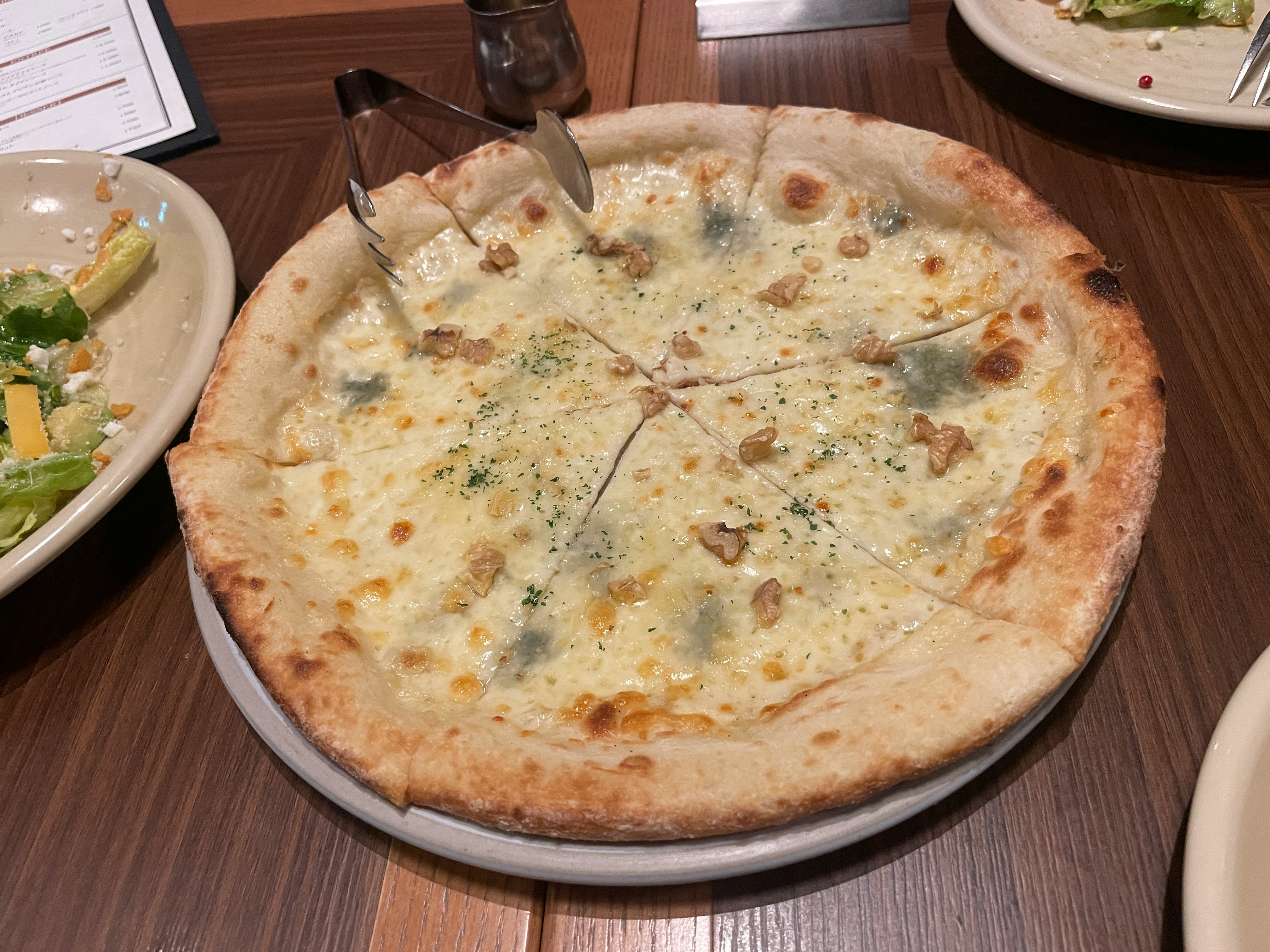 テーブル上のピザとサイドサラダの食事風景