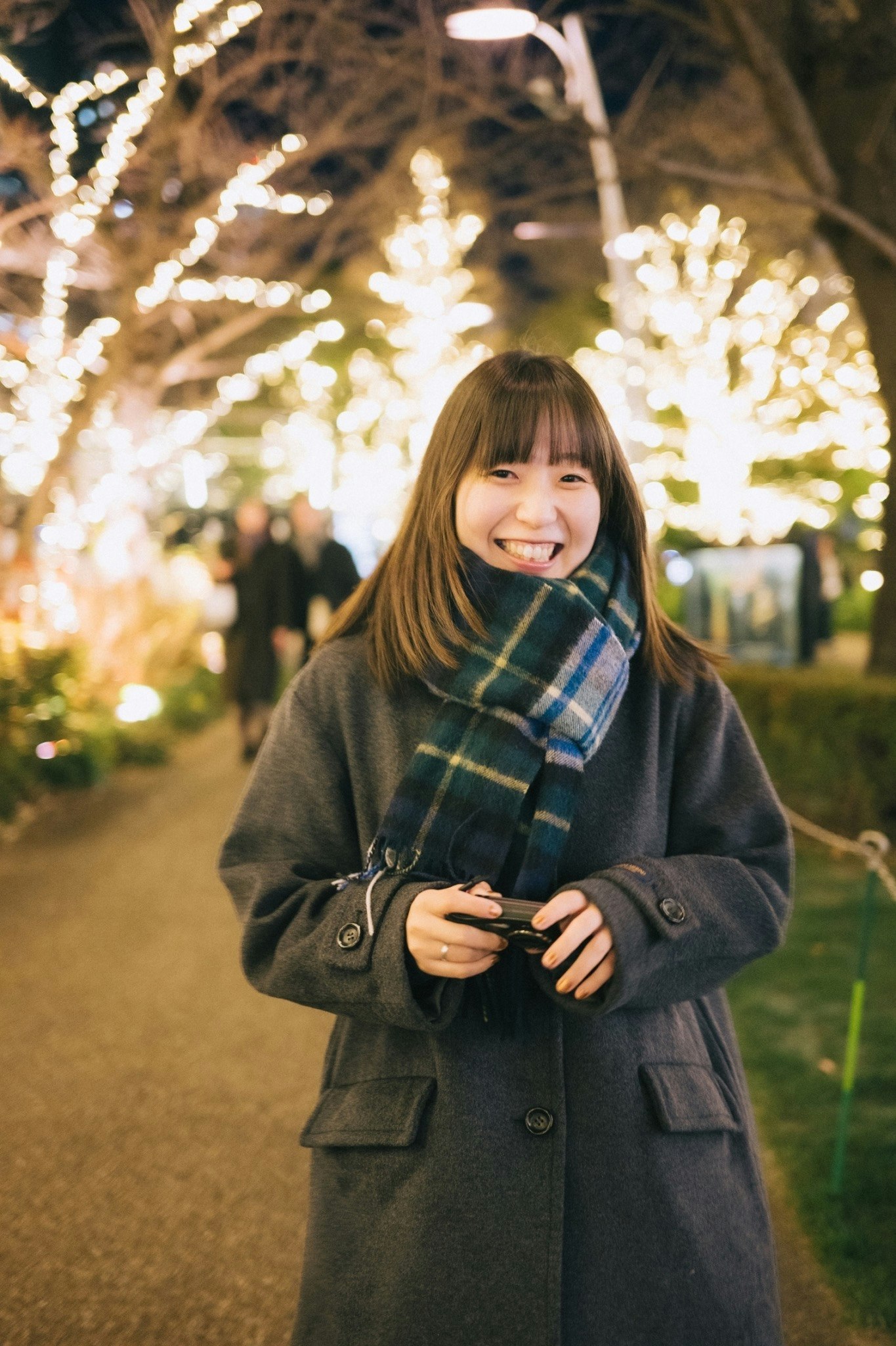 mujer sonriente con bufanda en un parque iluminado