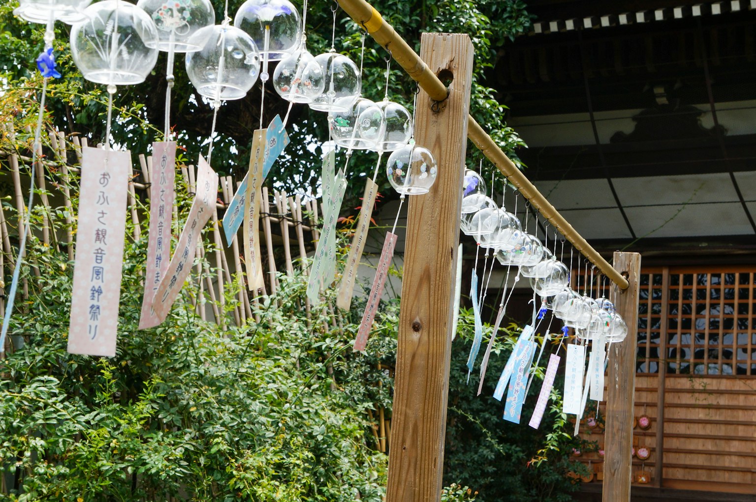 Holzpfeiler mit Windspielen und bunten Tanzaku in einem Garten