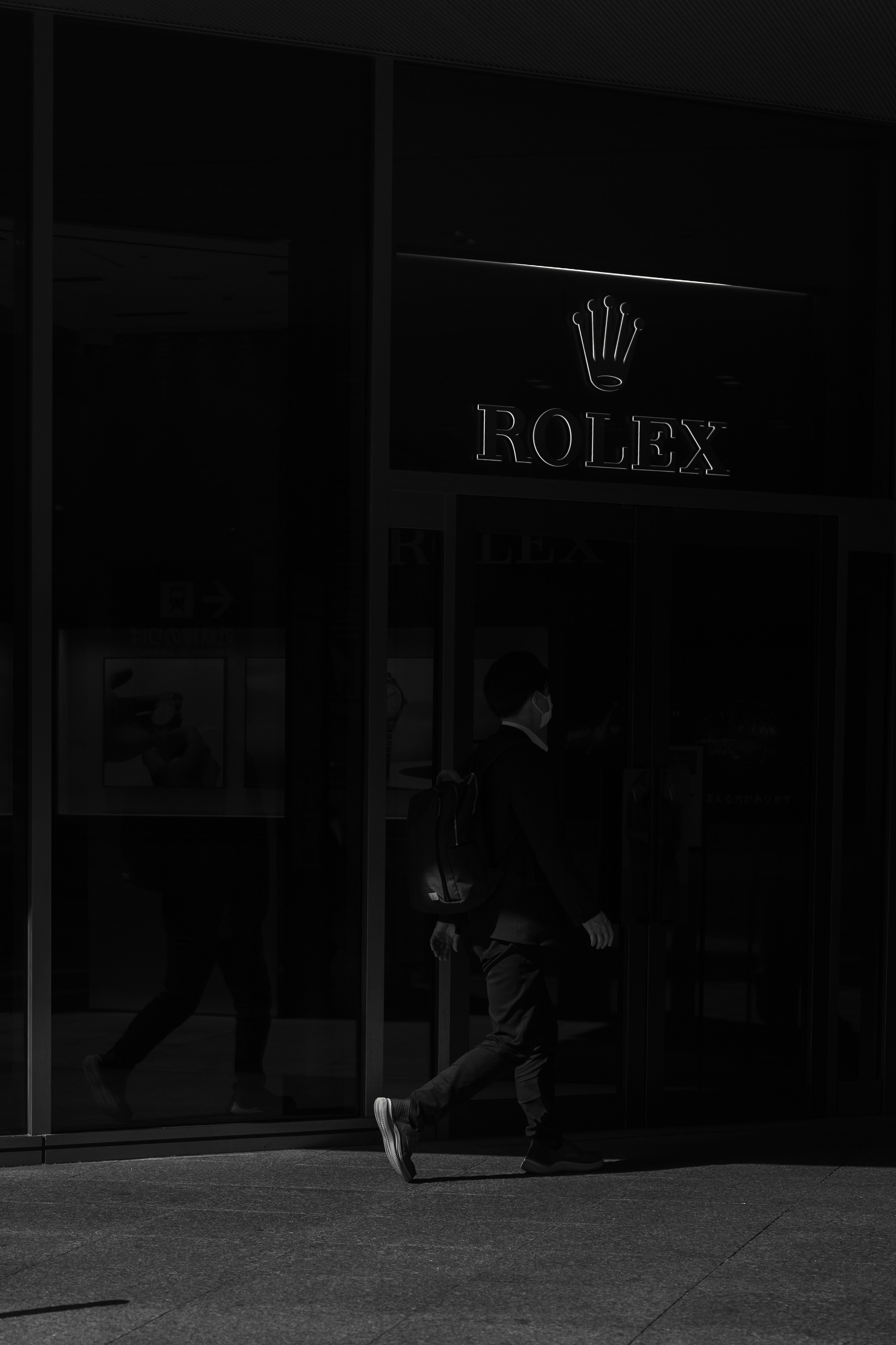 ROLEXの看板と光と影の強い路面のある店先