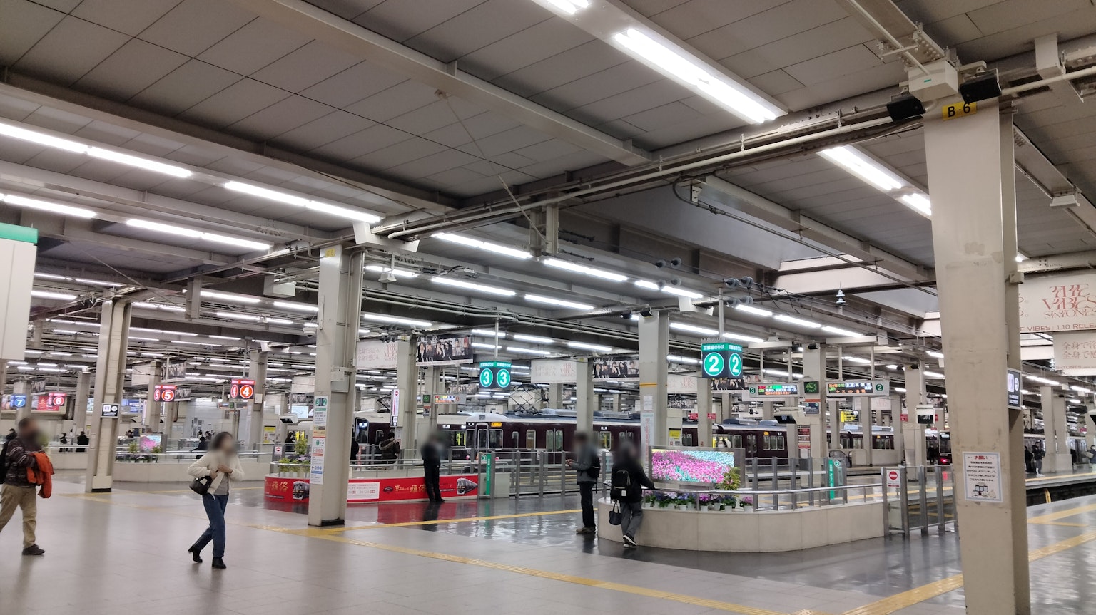 Interior espacioso de una estación de tren con personas en movimiento y diseño de iluminación moderna