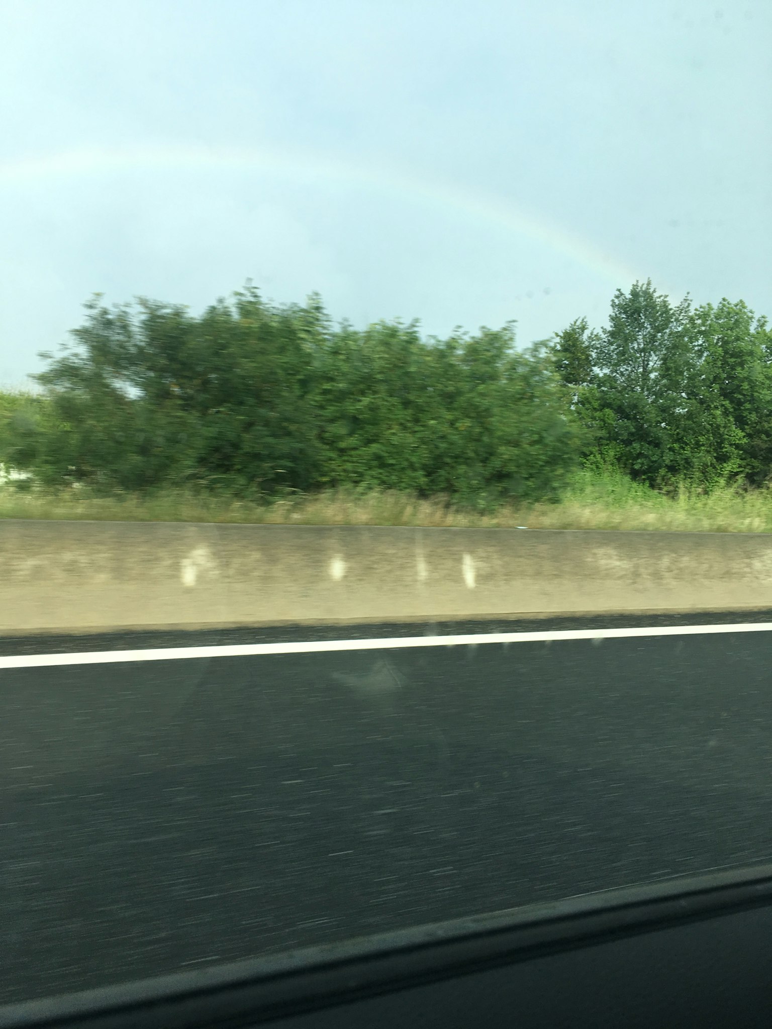 Vue pittoresque de verdure et d'un arc-en-ciel le long d'une route