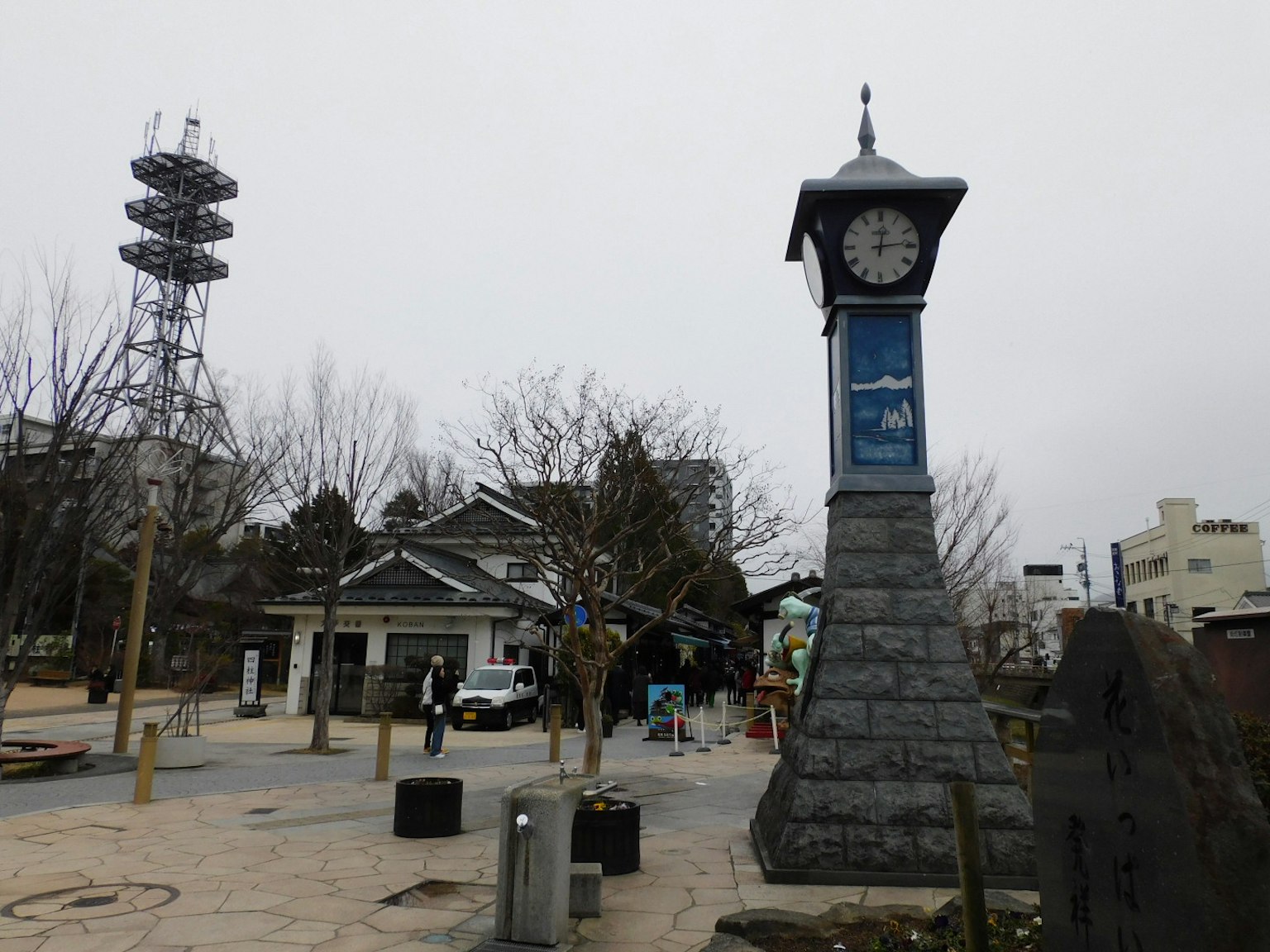 Blick auf einen Uhrturm und einen Kommunikationsturm in einem Park
