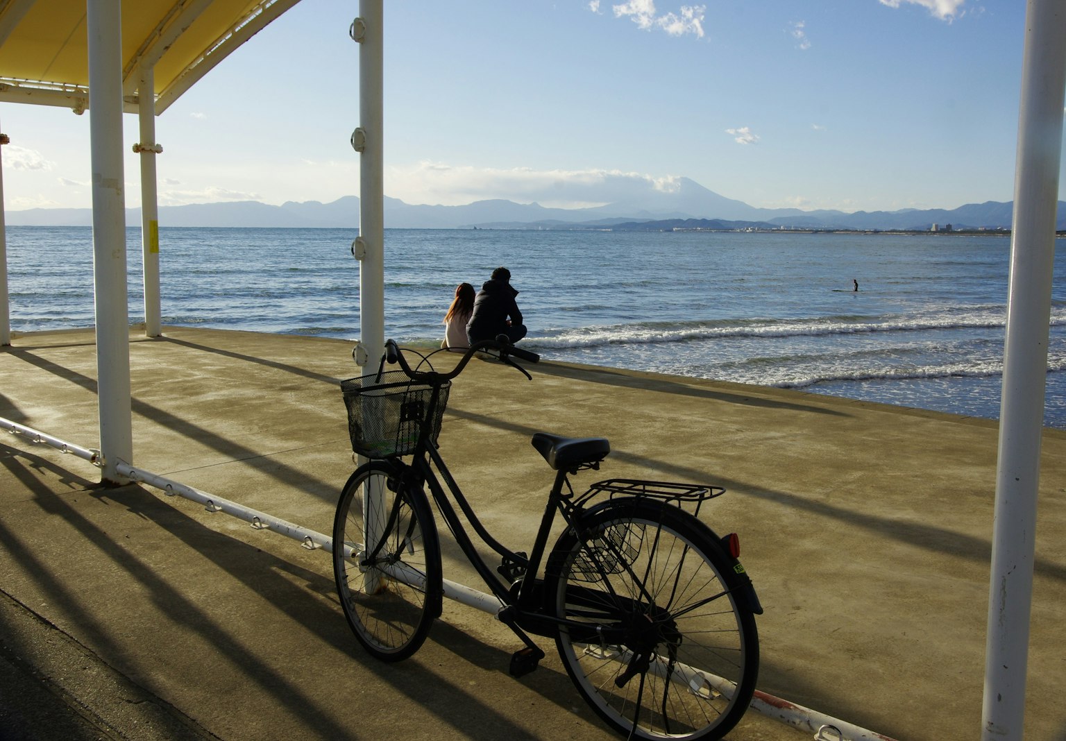 Bicicleta junto al mar con una persona sentada cerca