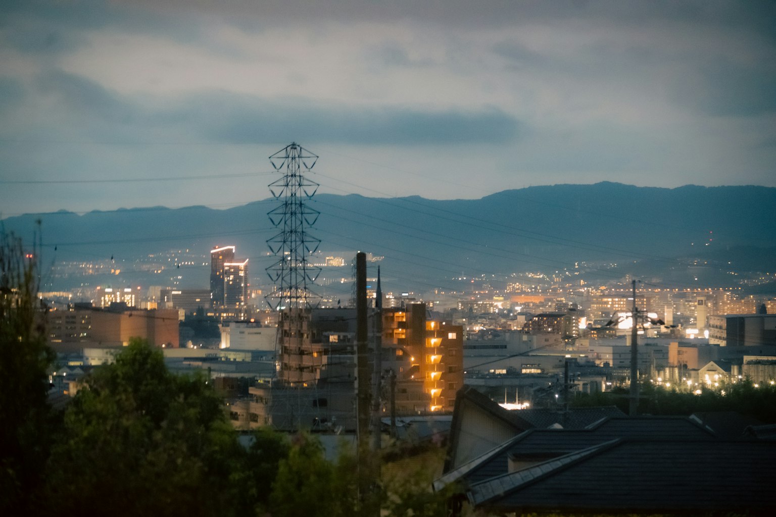 Scena notturna urbana con edifici illuminati e montagne sullo sfondo