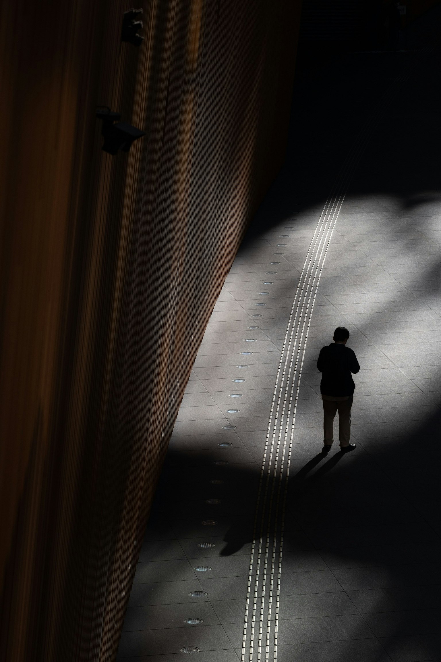 Silueta de una persona de pie en sombras con un contraste de luz impactante en un entorno urbano