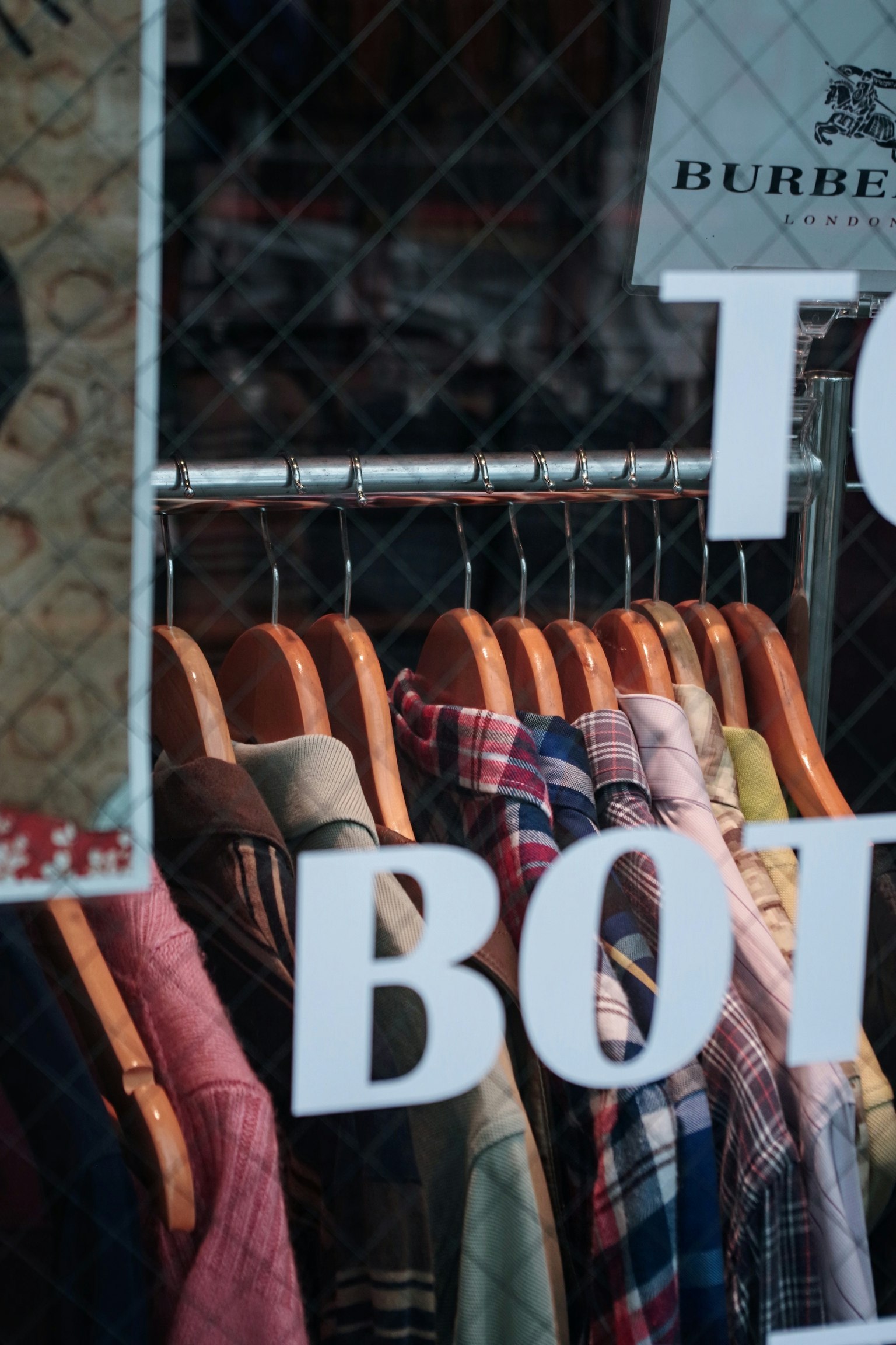 Collection colorée de chemises suspendues dans une vitrine avec le mot "BOTT"