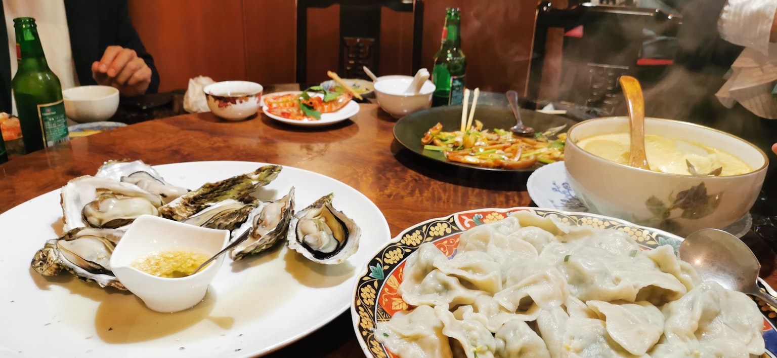 Impostazione del tavolo con frutti di mare tra cui ostriche fresche ravioli e zuppa calda