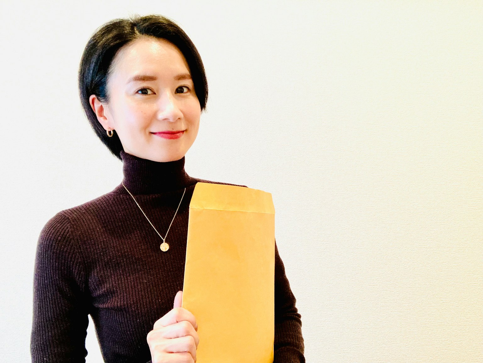 一位女性微笑着拿着一个棕色信封